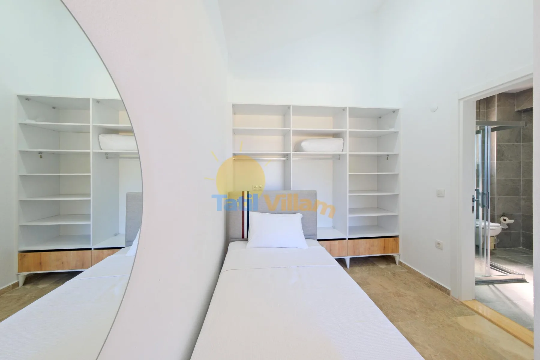 Un dormitorio luminoso con una cama y estanterías empotradas junto a la pared.