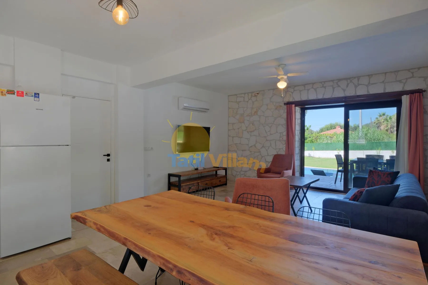 Una zona abierta de comedor y sala tiene una mesa de madera y puertas corredizas de vidrio.