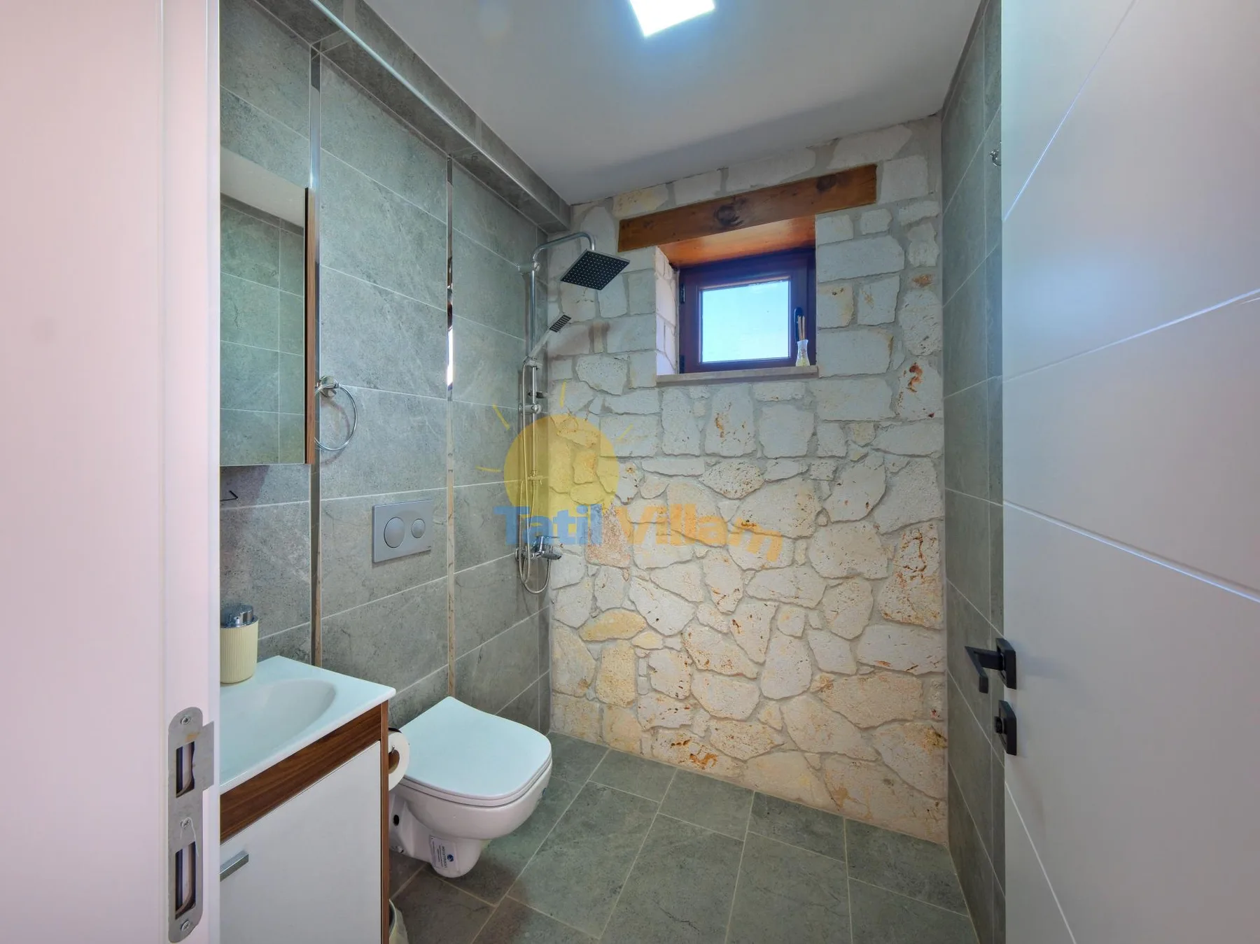 Un baño revestido de azulejos con ducha, inodoro y una ventana pequeña.