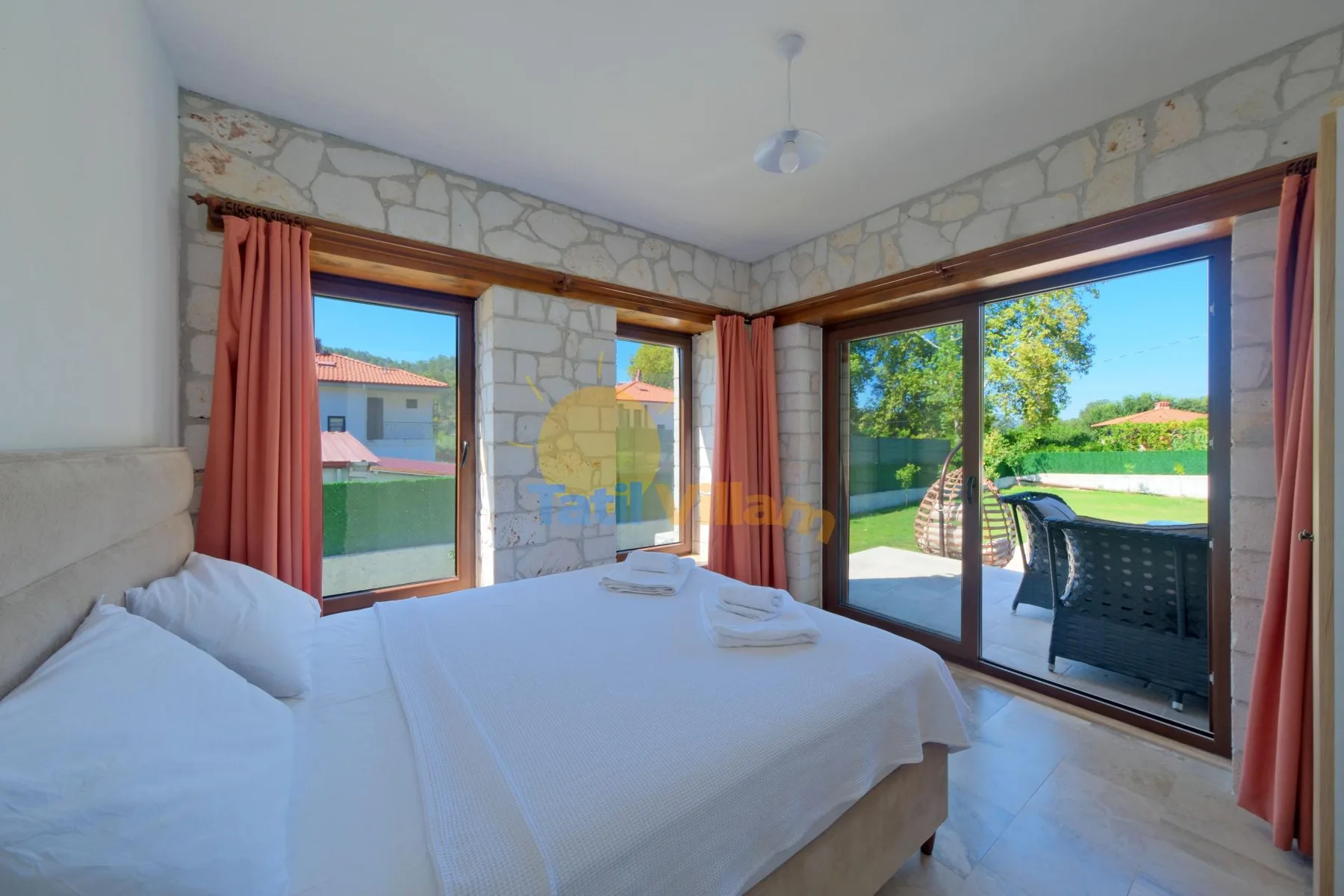Un dormitorio luminoso con una cama junto a grandes ventanas con vistas al jardín.