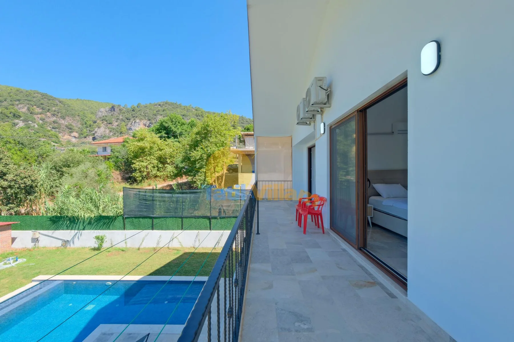 Una terraza exterior con suelo de baldosas da a una piscina y colinas verdes.