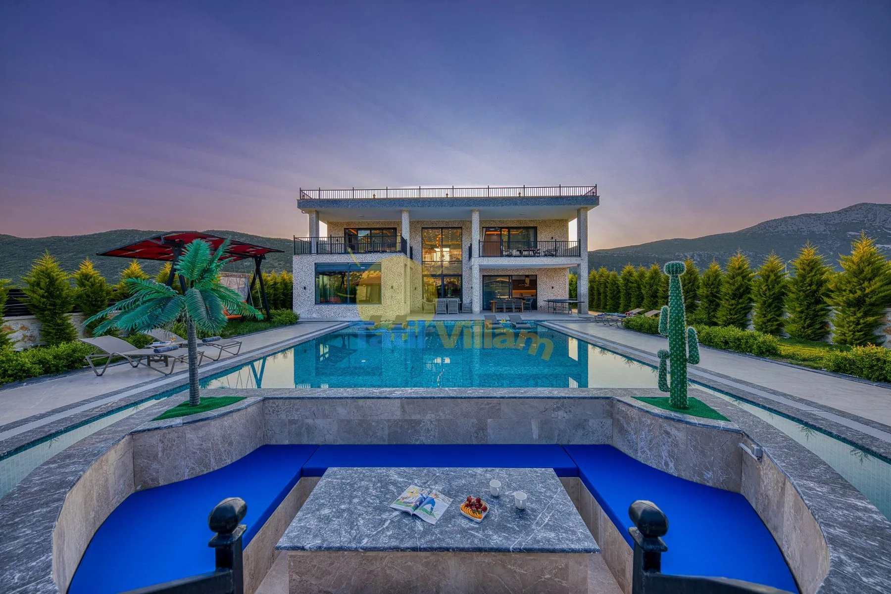 An outdoor swimming pool faces a modern building, with a blue-lit basin in the foreground.
