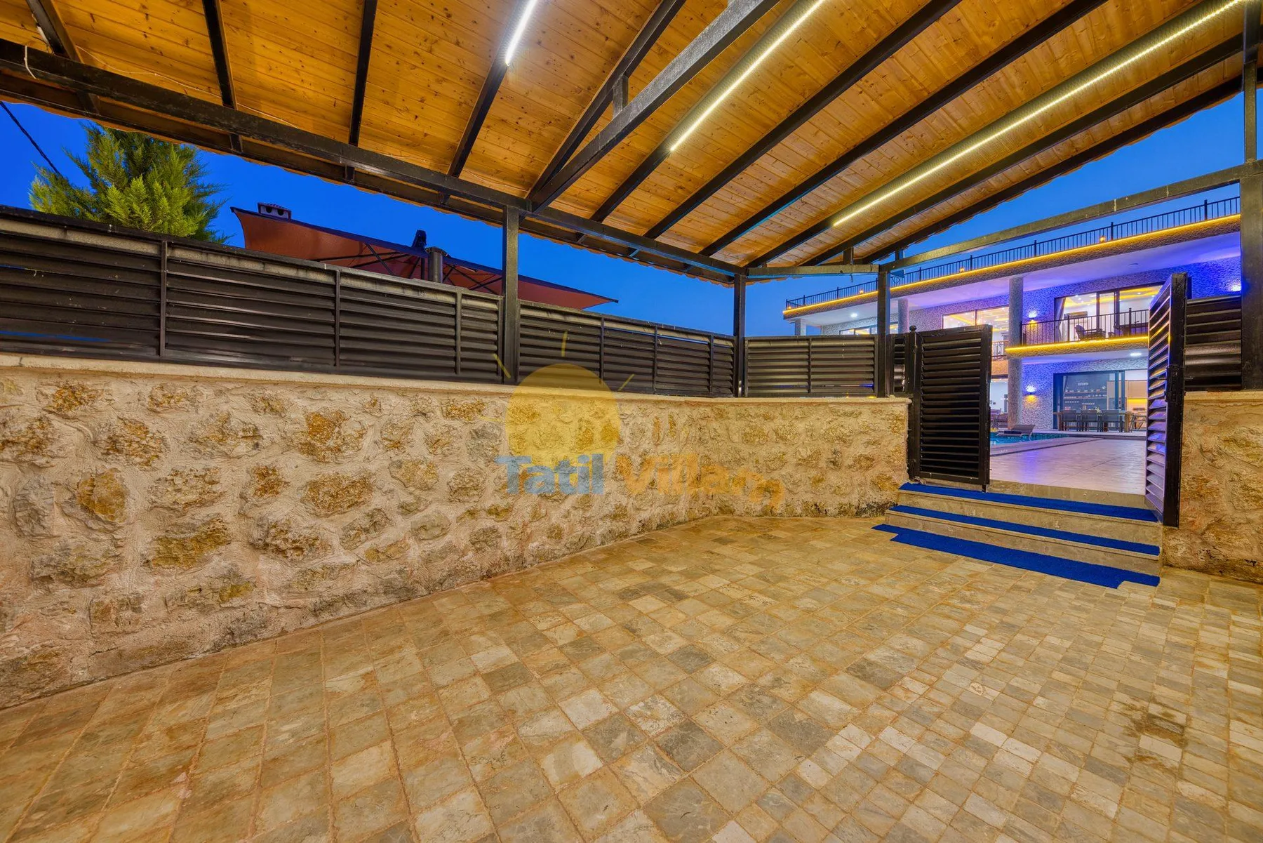 A covered outdoor patio with stone walls and an open gate.