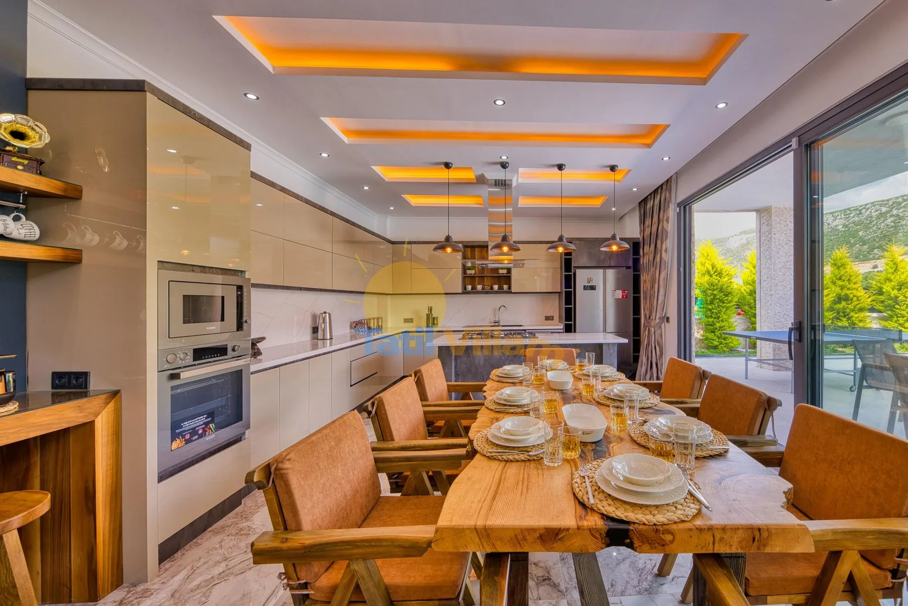 A dining area with a long wooden table set with dishes beside large glass doors.