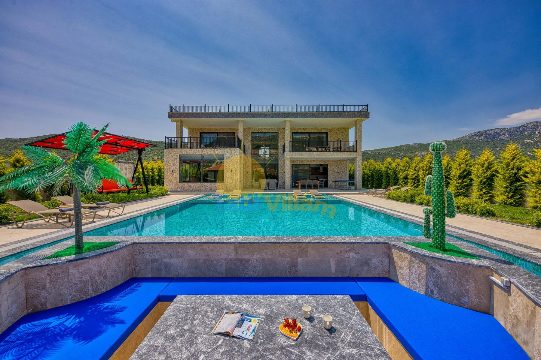 A modern house stands beyond a swimming pool, with a patio table in the foreground.