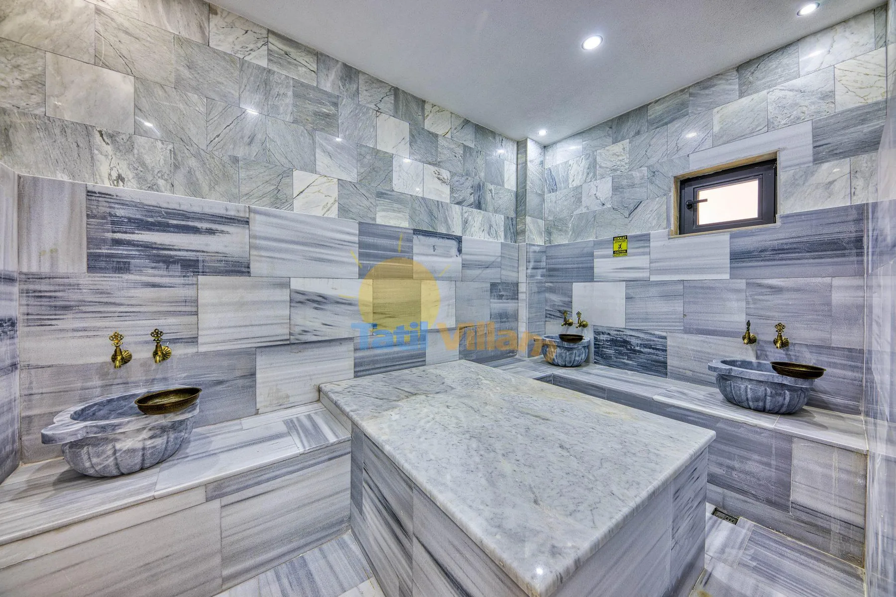 A marble-tiled bathroom with a central stone counter and basins along the walls.