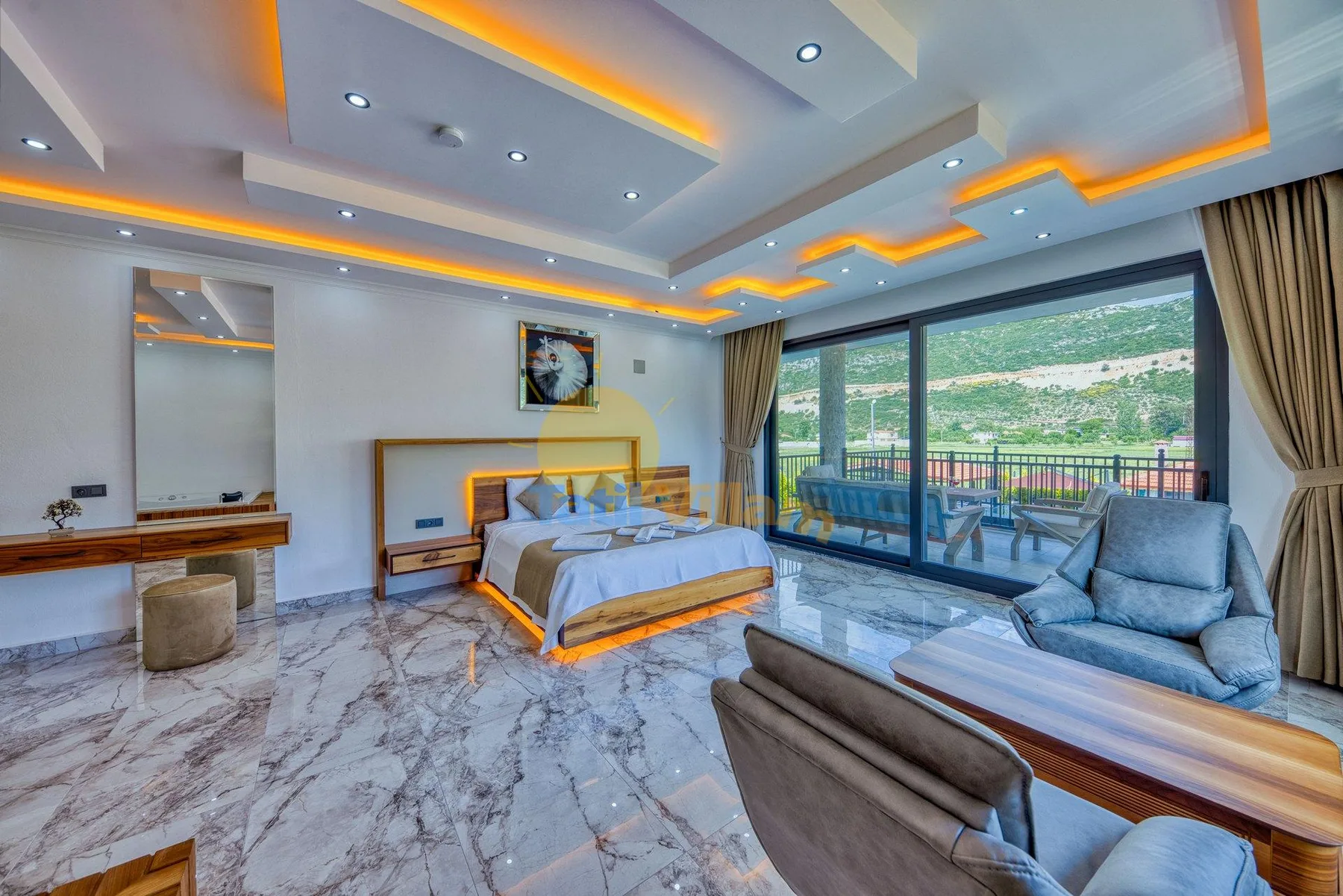 A bedroom with a bed and seating beside glass doors opening onto a balcony.