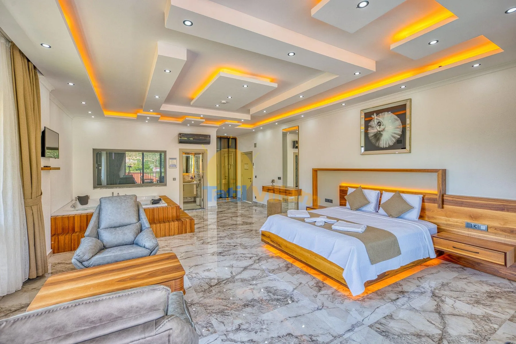 A bedroom with a bed and seating beneath a decorative recessed ceiling.