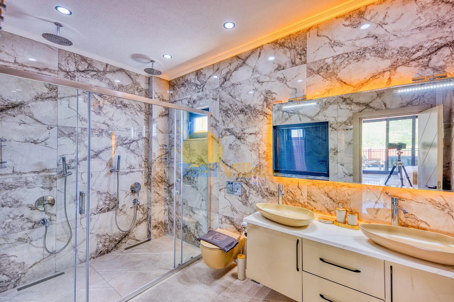 A marble-tiled bathroom with a glass shower and double-sink vanity.