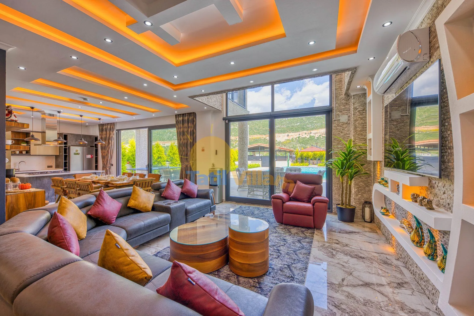 A bright living room with seating, round tables, and large windows opening onto a balcony.