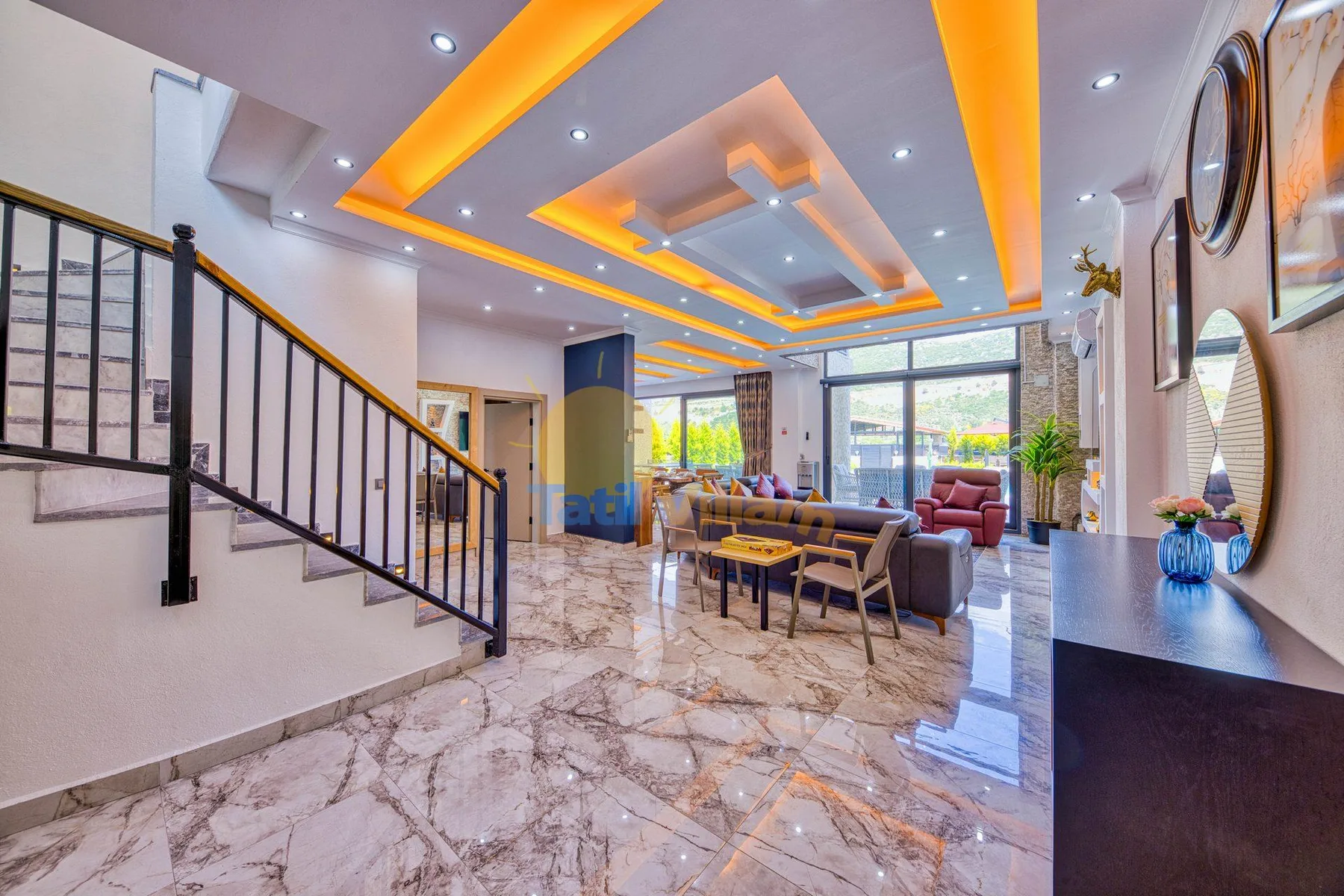 A bright living room with seating beneath a ceiling with orange accent lighting.