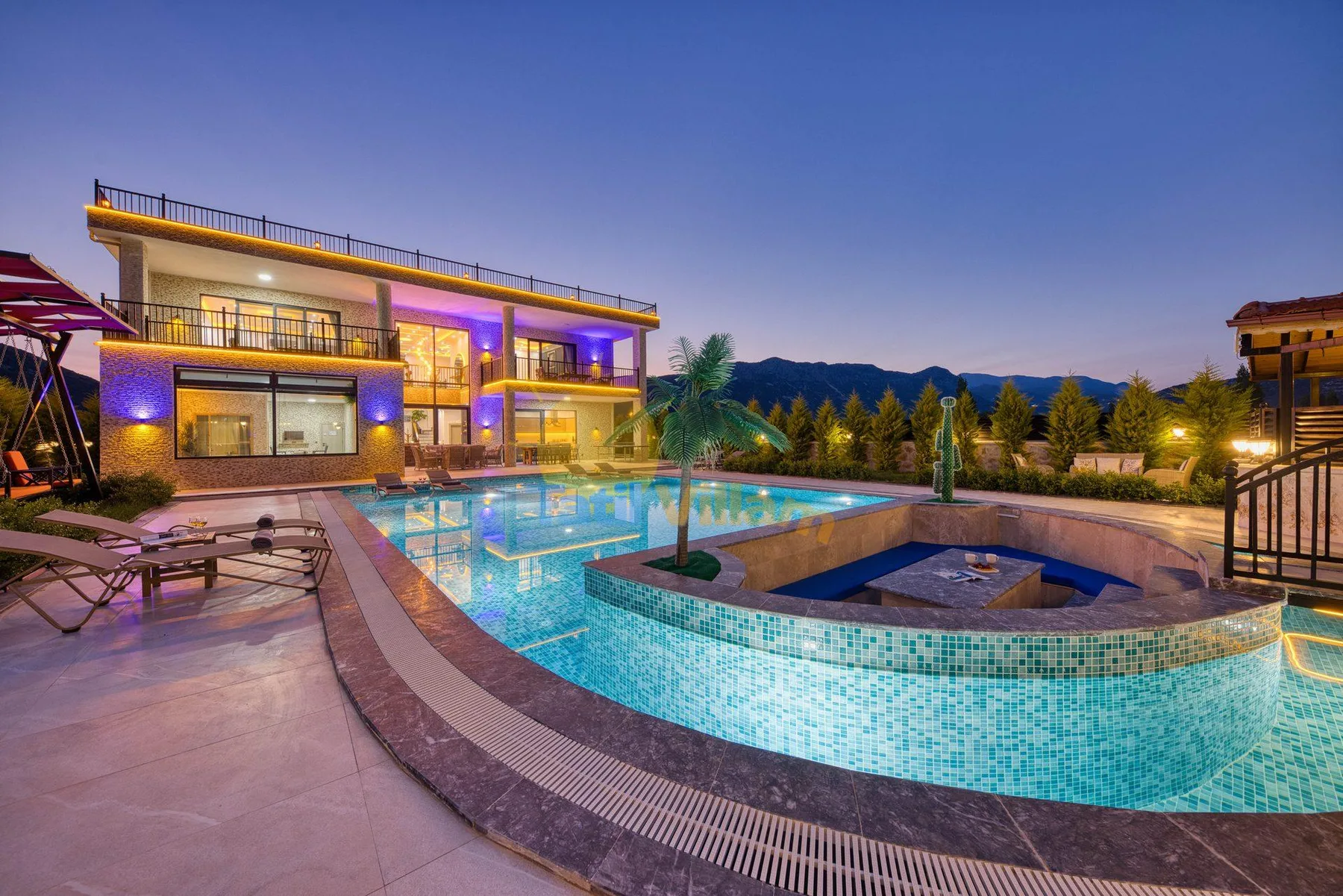 An outdoor swimming pool curves around a raised spa beside a modern building.
