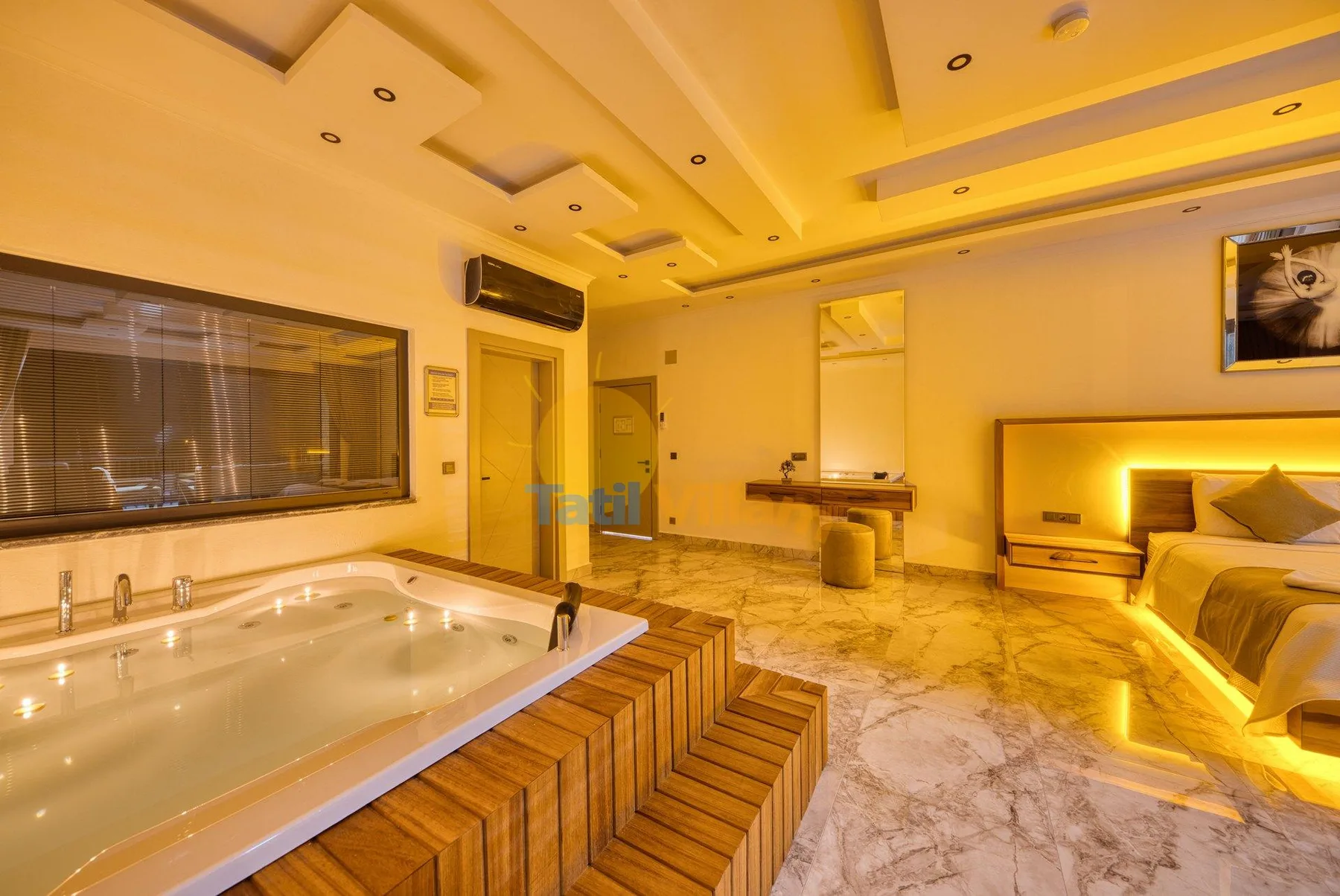 A warmly lit bedroom with a built-in soaking tub and a bed.