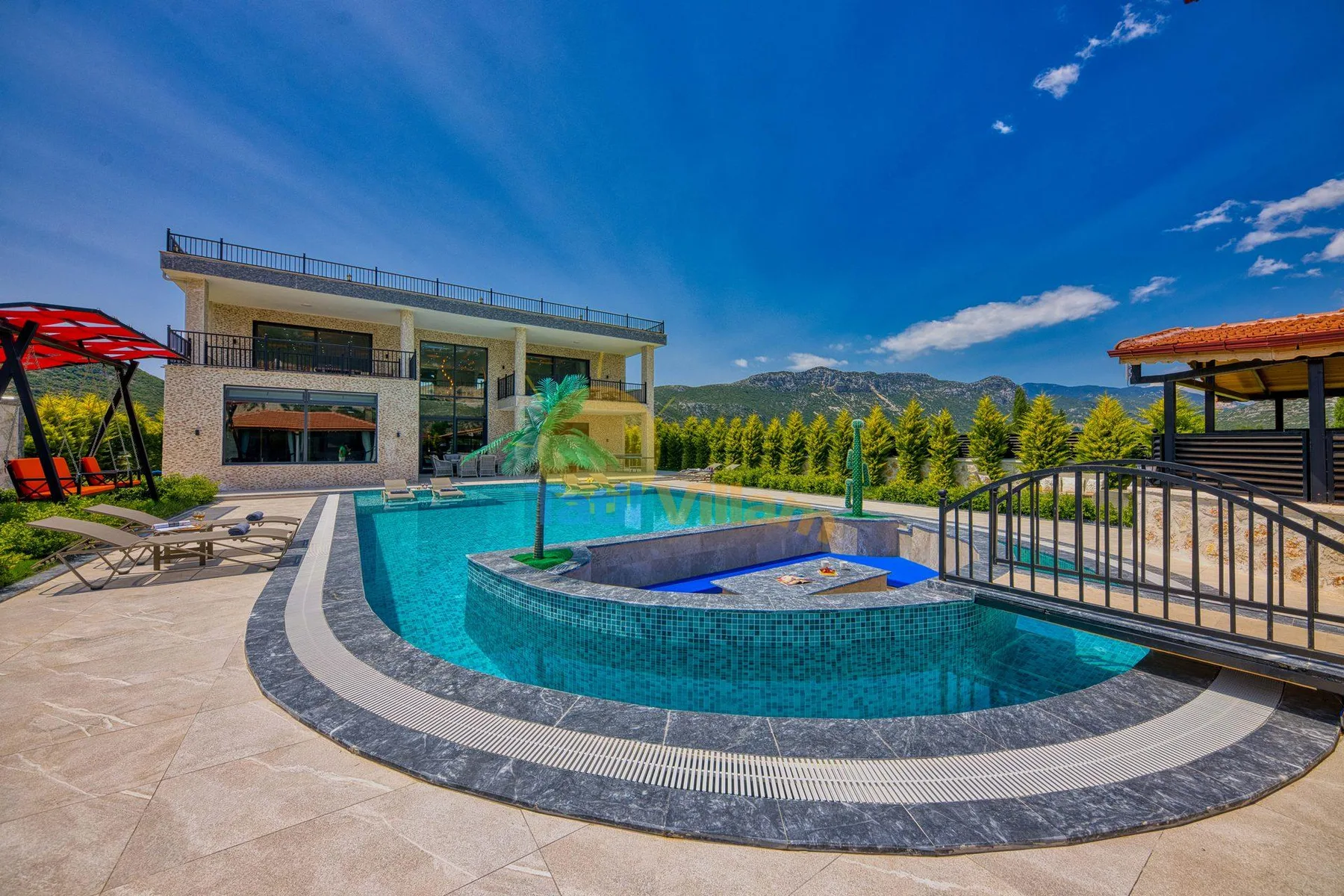 An outdoor swimming pool curves around a raised spa beside a modern building.
