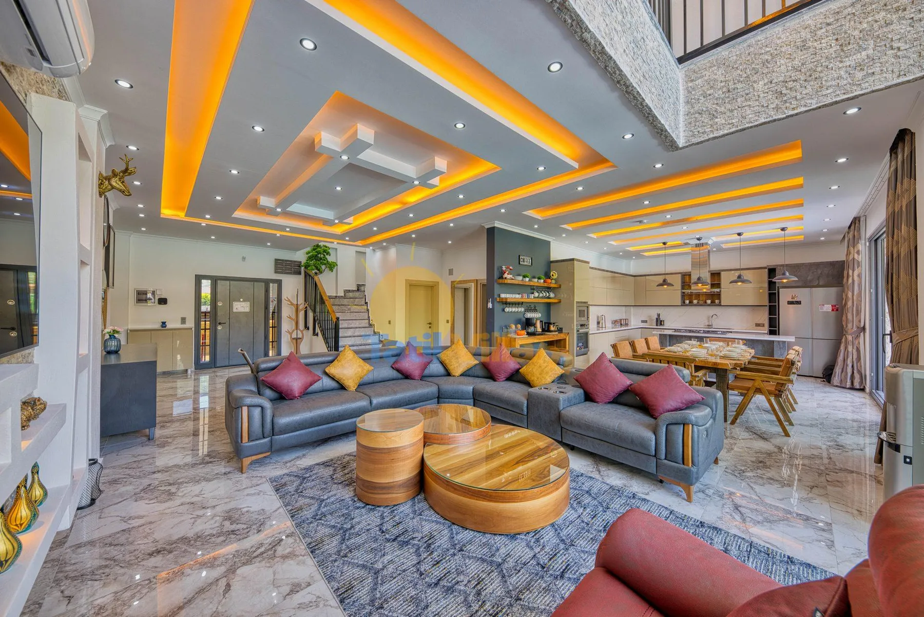 A spacious living room with sectional seating and a dining area beneath a lit ceiling.