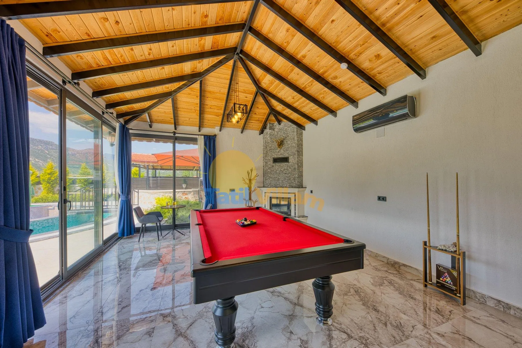 A game room with a red pool table beneath a timber ceiling.