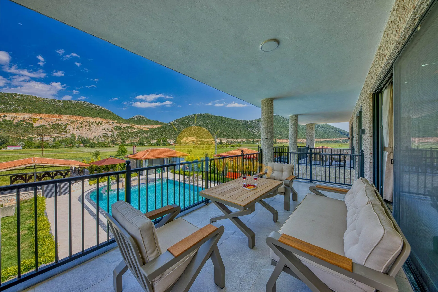 A covered patio overlooks a swimming pool and the surrounding hills.