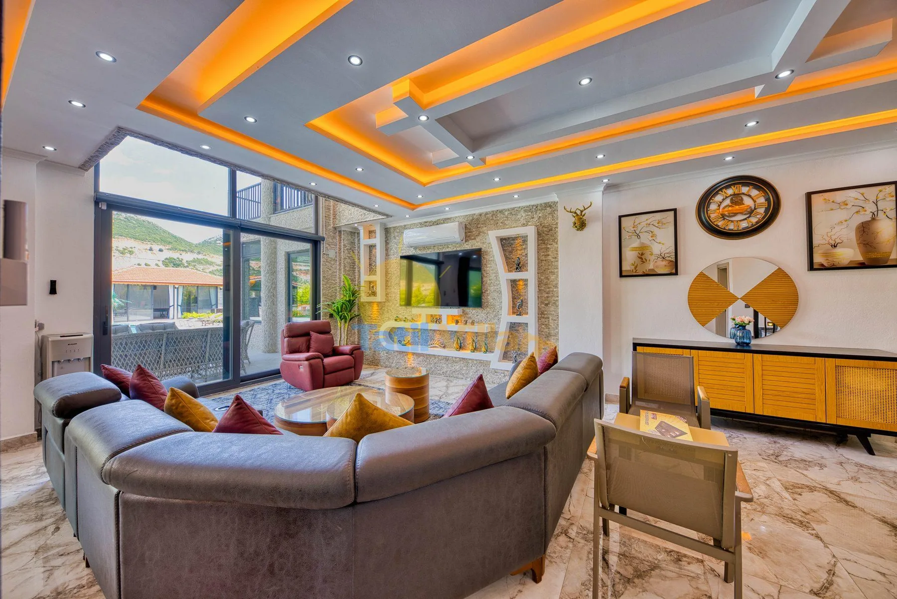 A living room with curved seating, a coffee table, and large windows.