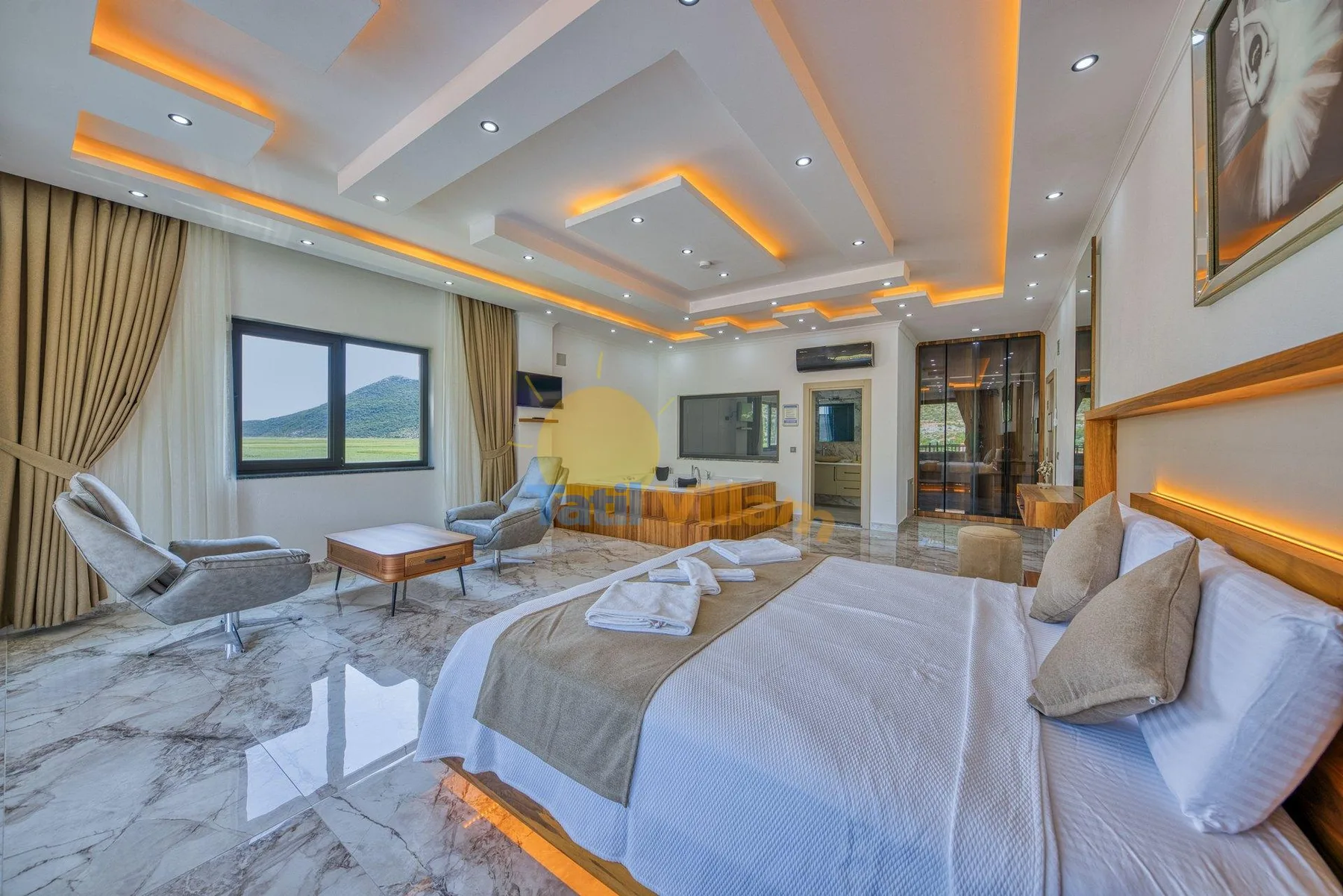 A bedroom with a large bed, seating area, and recessed ceiling lights.