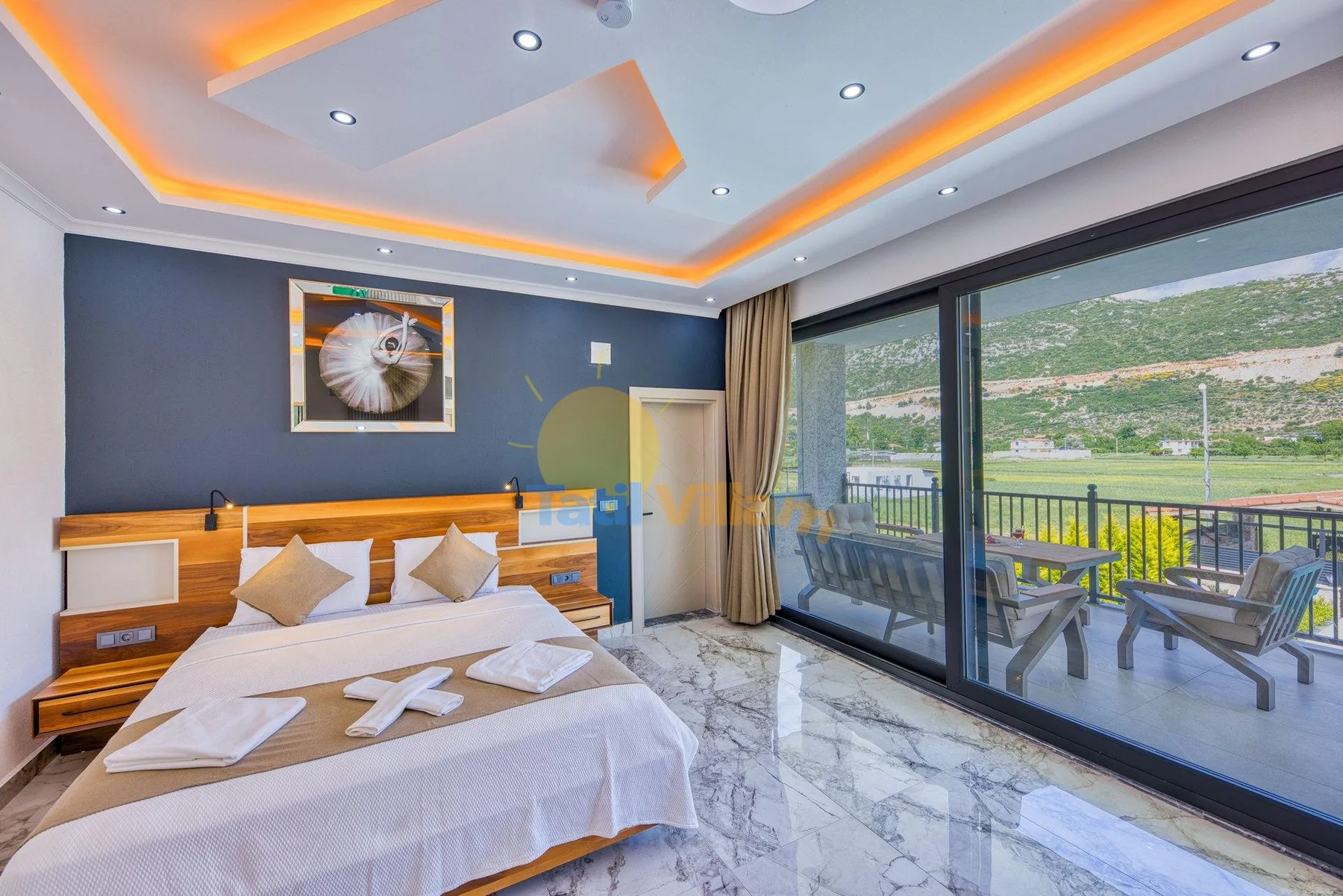 A bedroom with a neatly made bed beside large glass doors opening onto a balcony.