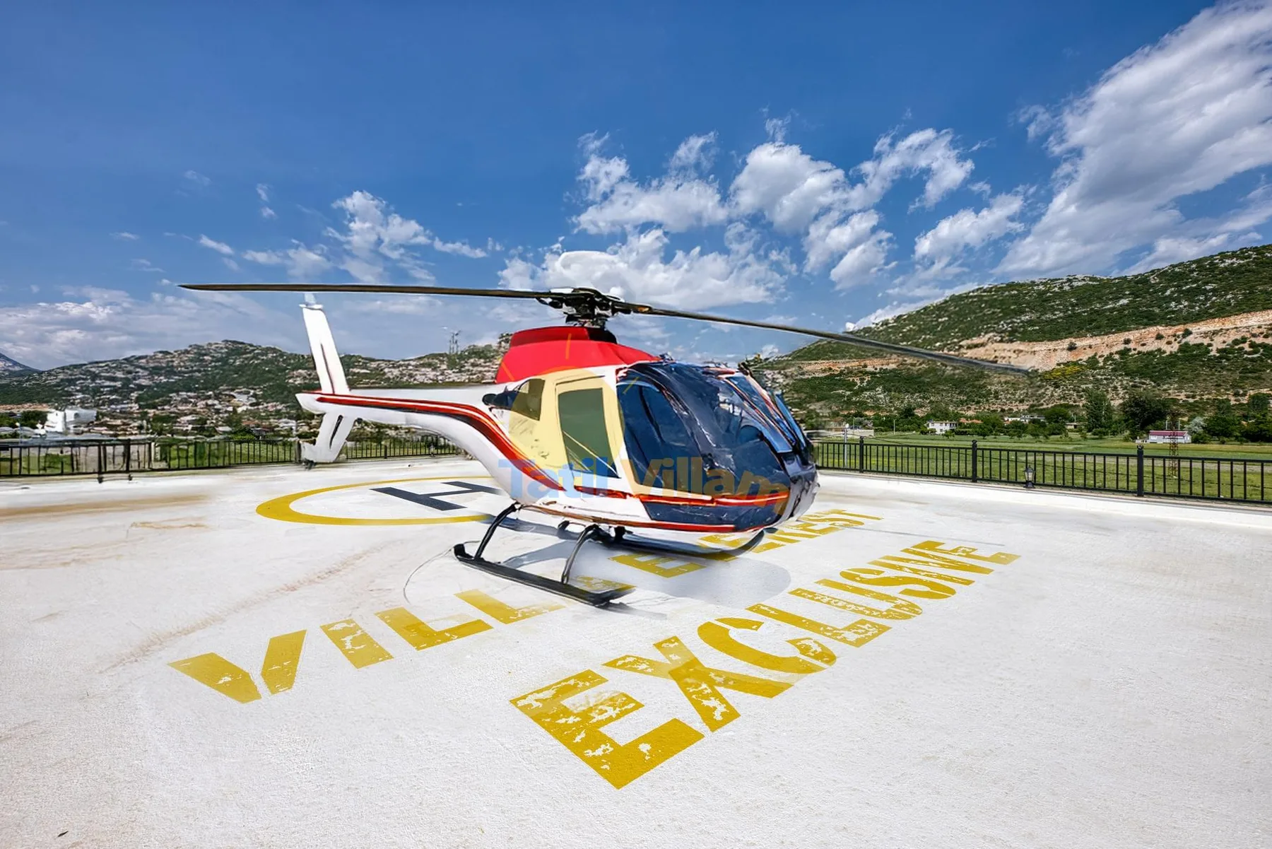 A helicopter sits on a marked landing pad with hills in the background.
