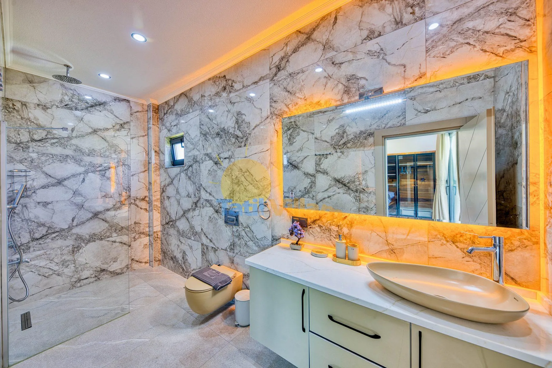 A marble-patterned bathroom features a large mirror above a vanity with a basin.
