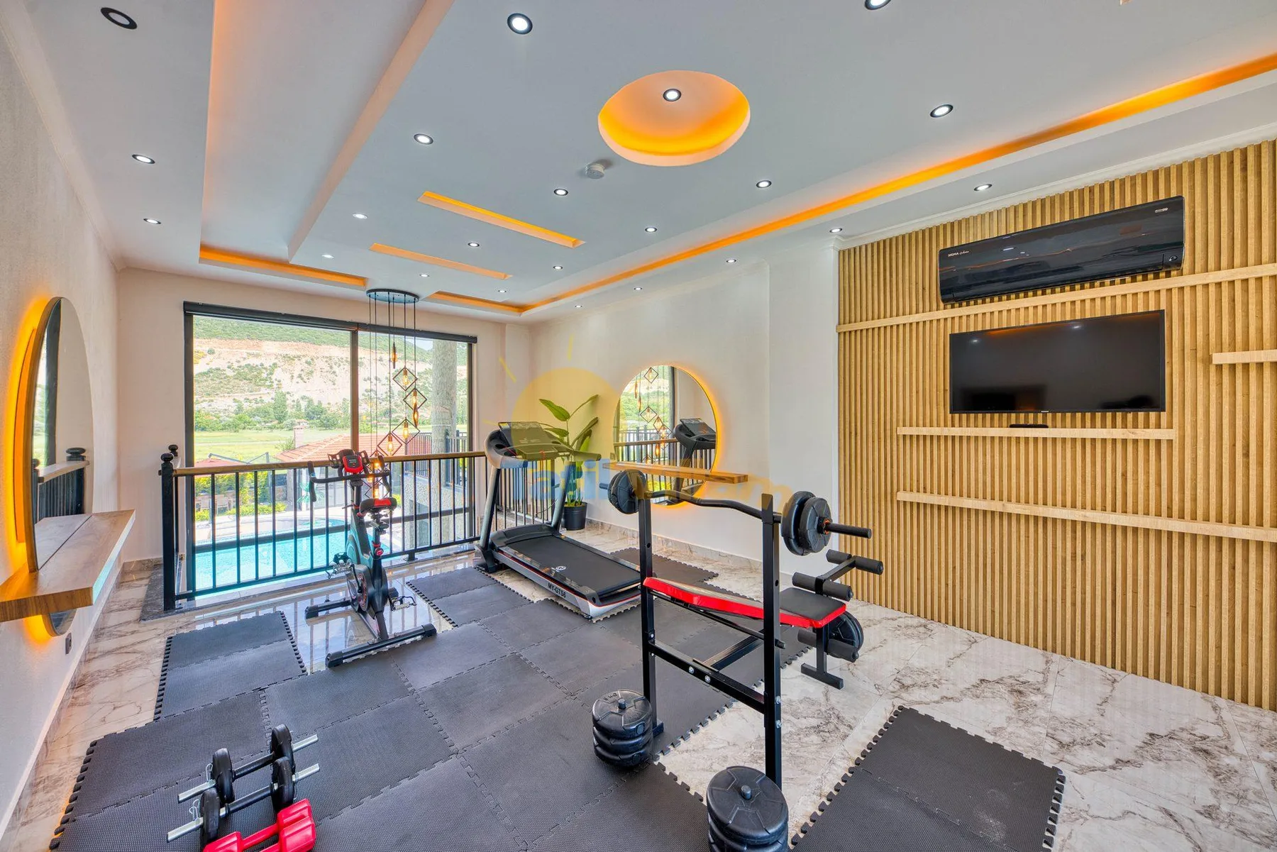 A home gym with exercise equipment, weight racks, and large windows.