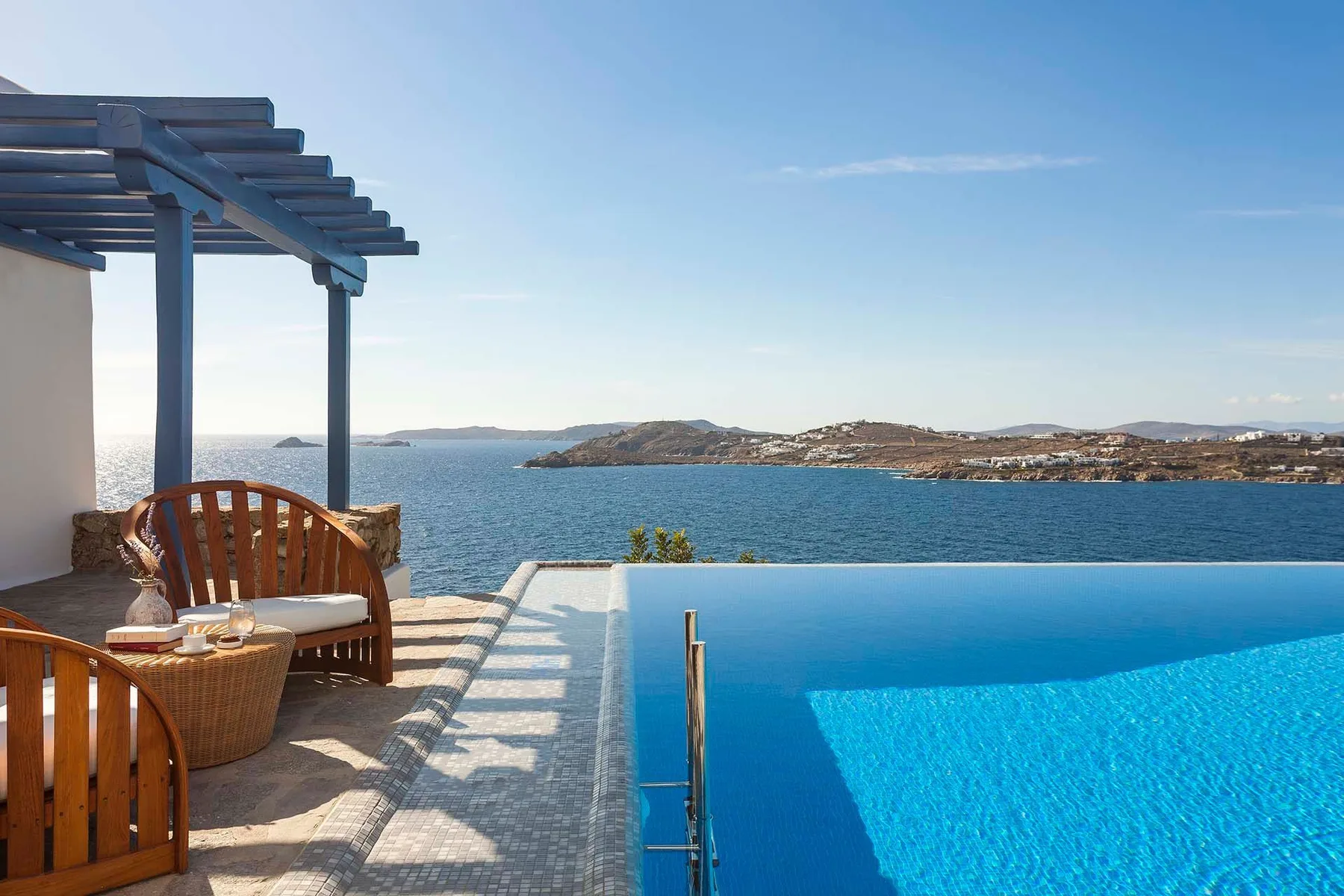A seaside terrace with a swimming pool and outdoor seating overlooks the water.