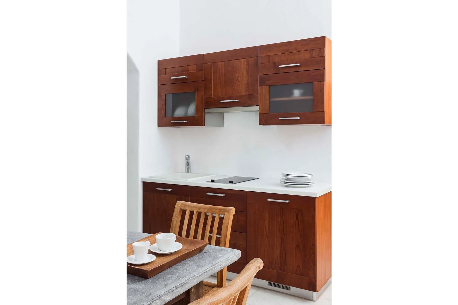 A compact kitchen with wooden cabinets, a sink, and a dining table.