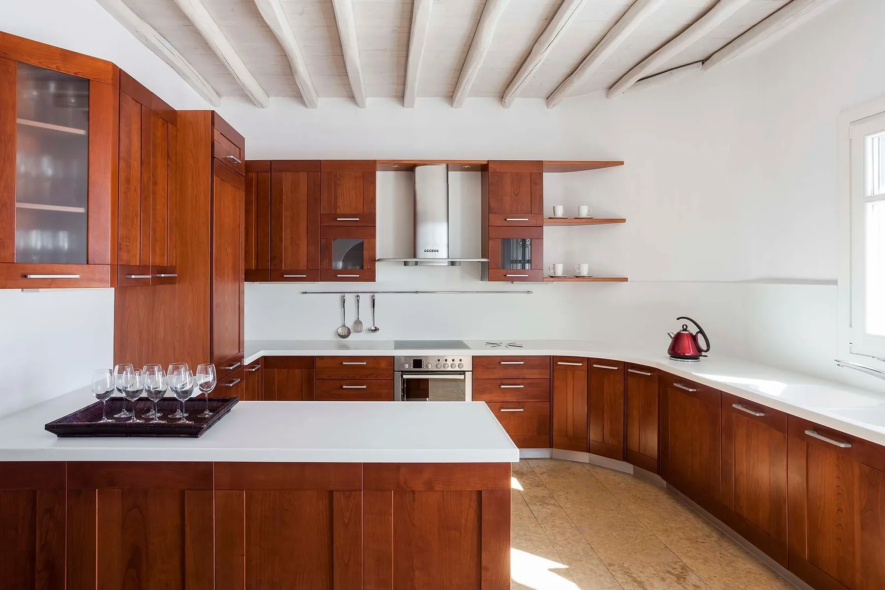 A spacious kitchen with reddish wooden cabinets, a central island, and white countertops.