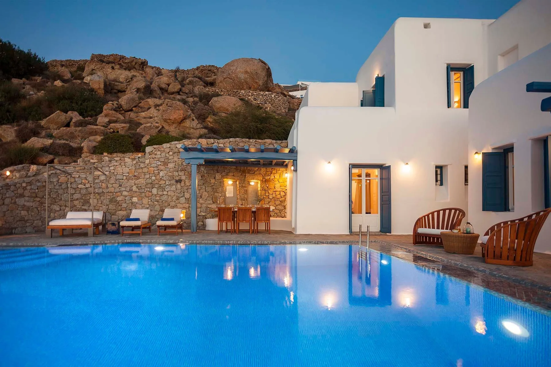 A swimming pool beside white buildings and an outdoor seating area.