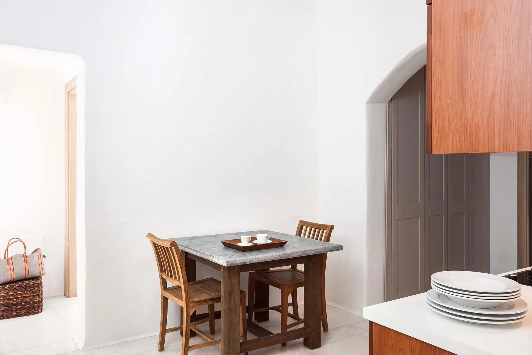 A small dining area with a wooden table and chairs beside an arched doorway.