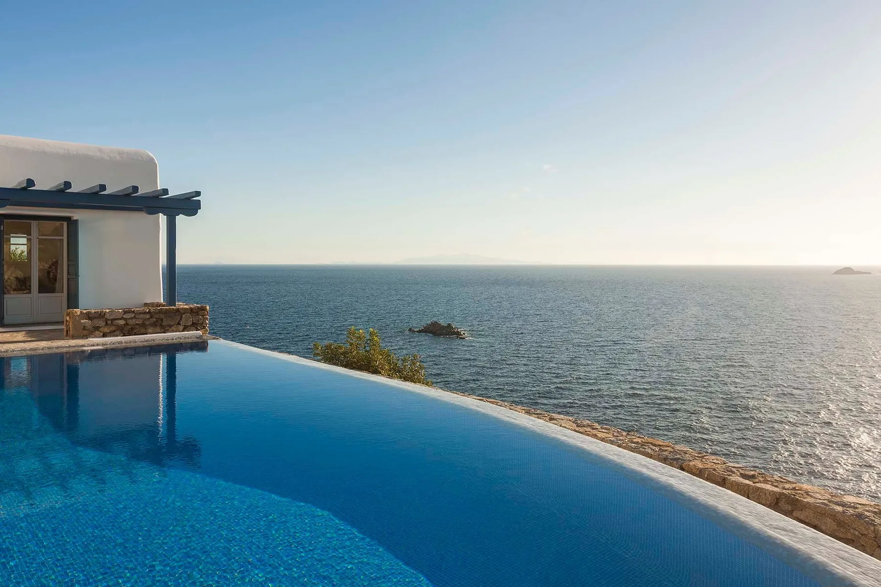 An infinity pool overlooks the sea beside a white building.