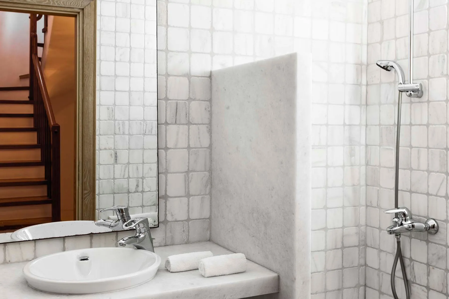A tiled bathroom with a sink and wall-mounted shower.