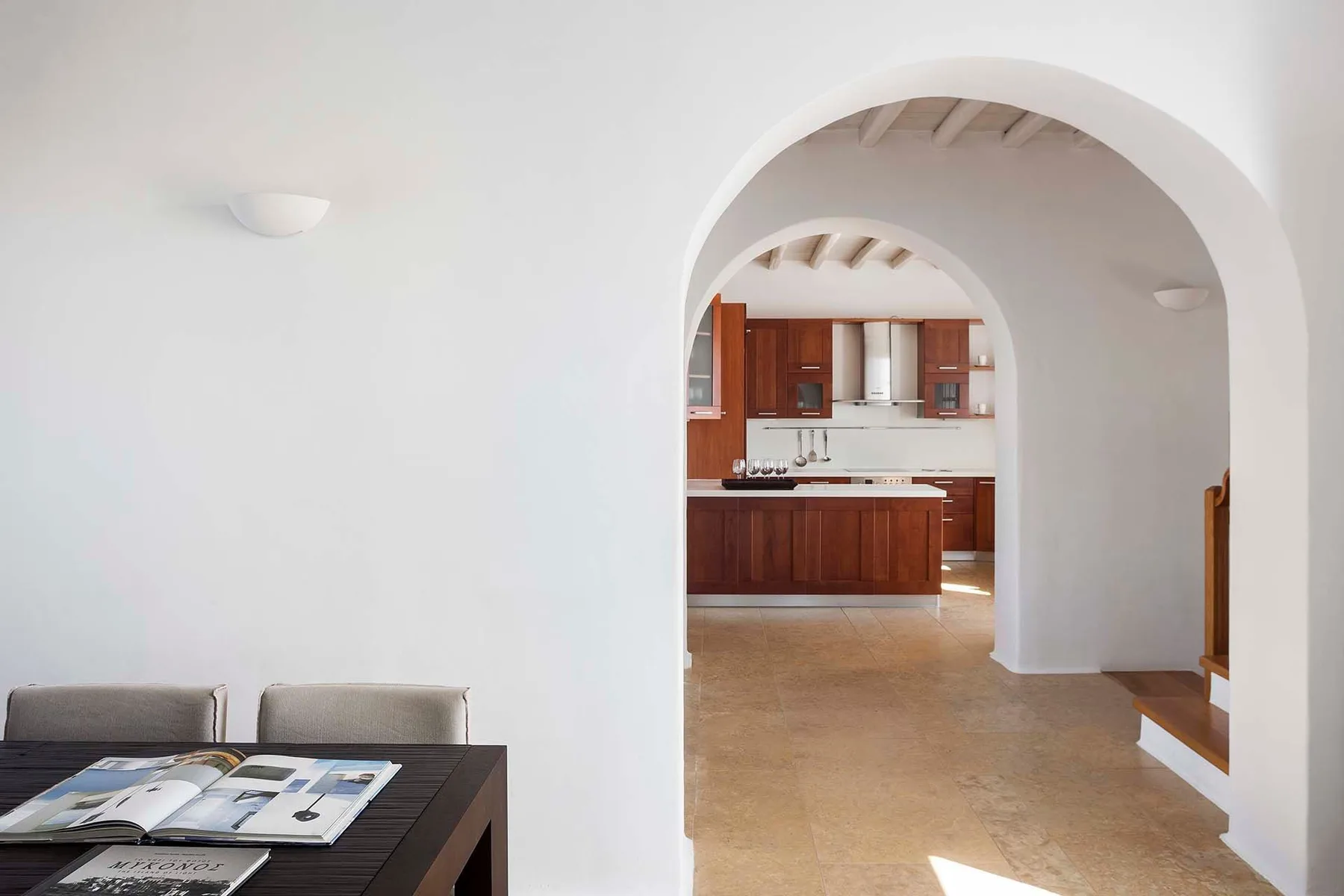 A dining area opens through an arched doorway into a kitchen.