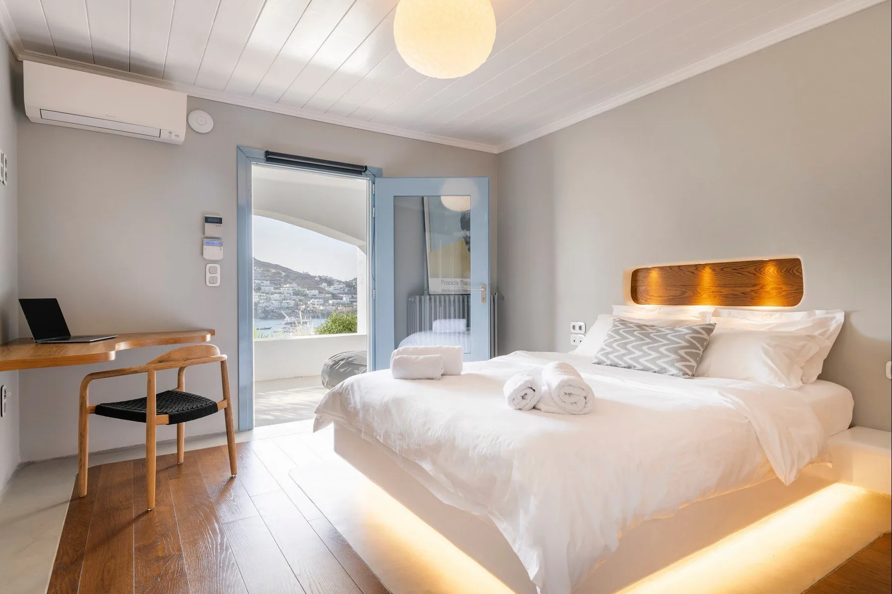 A bright bedroom with a neatly made bed and a desk beside the window.