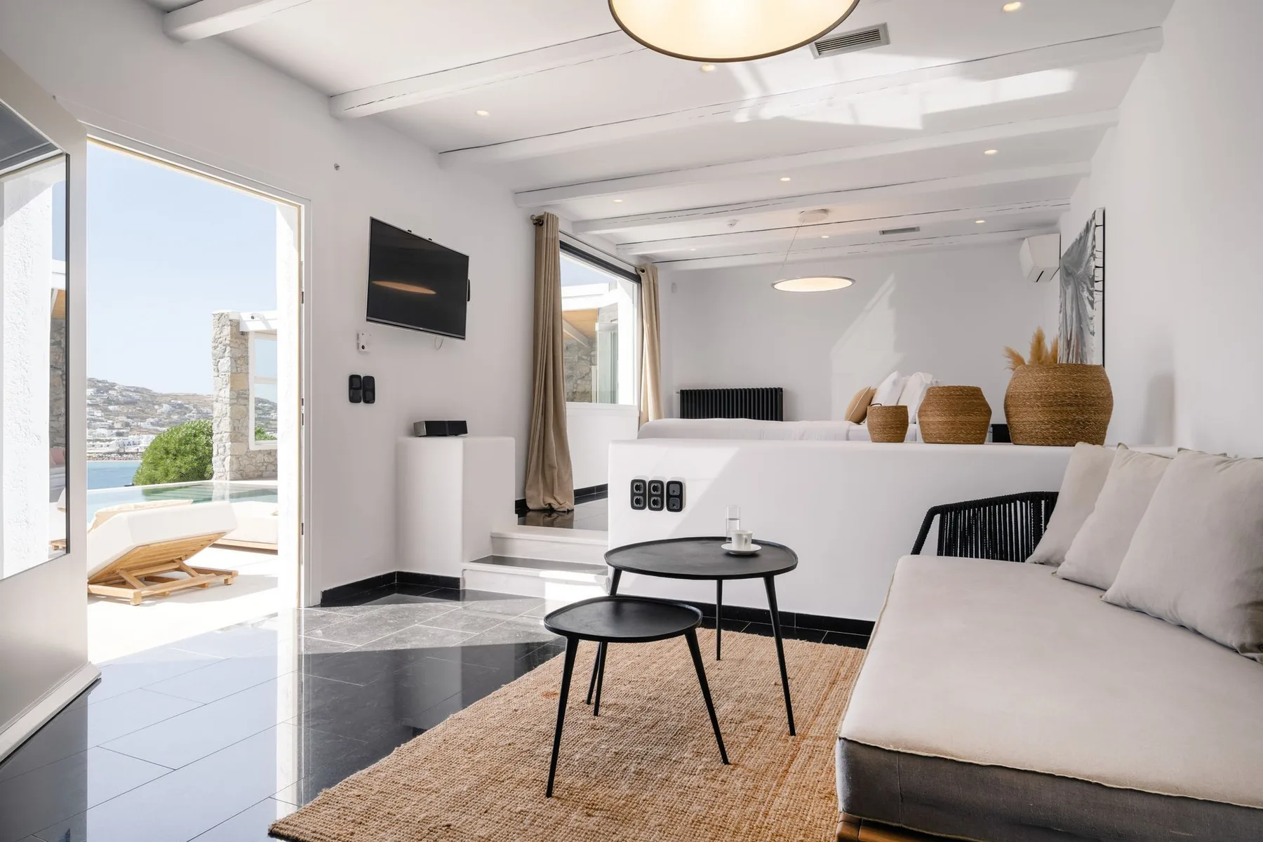 A bright living room with seating, a coffee table, and an open view to the patio.