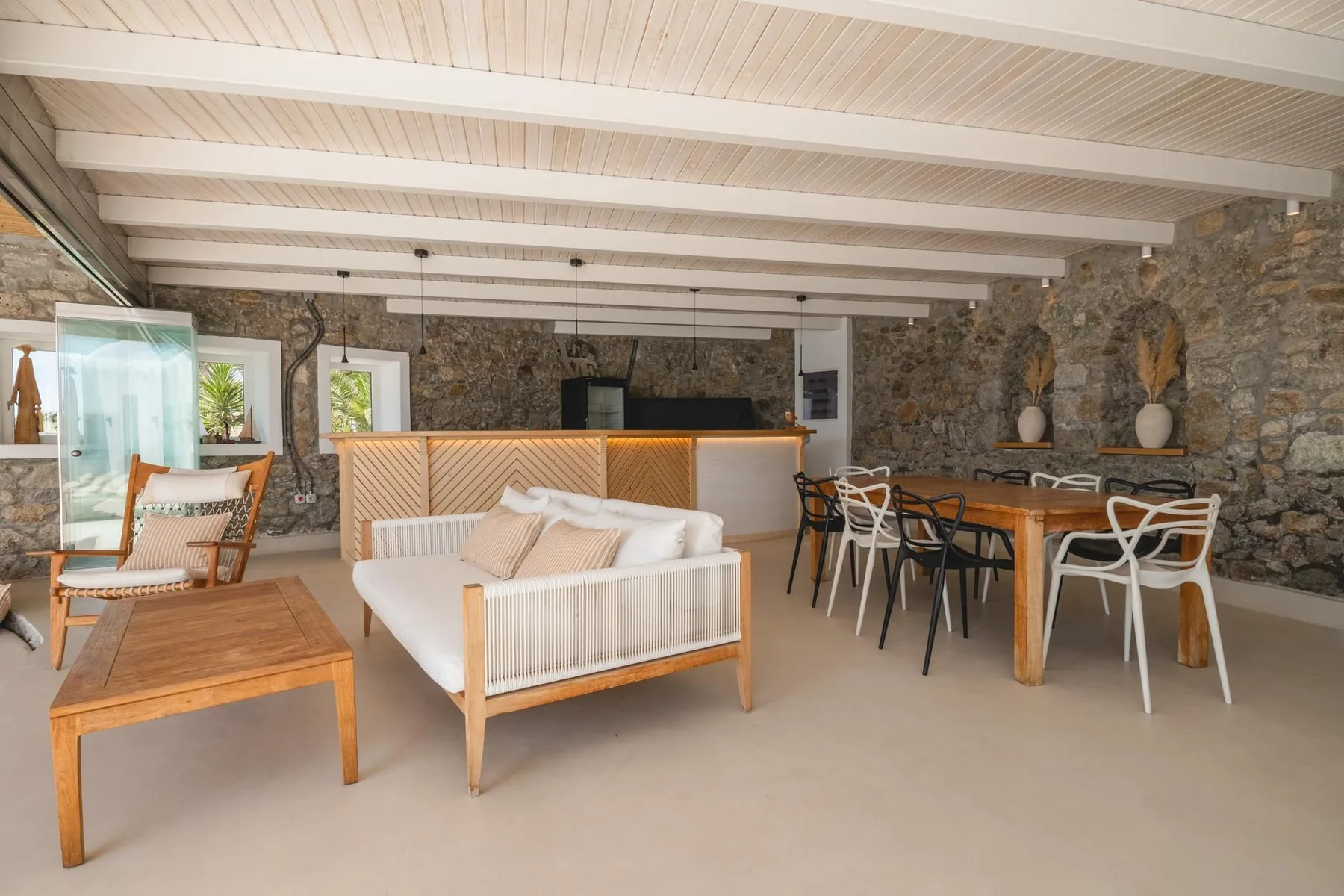 A stone-walled open-plan living and dining area with a sofa and dining table.