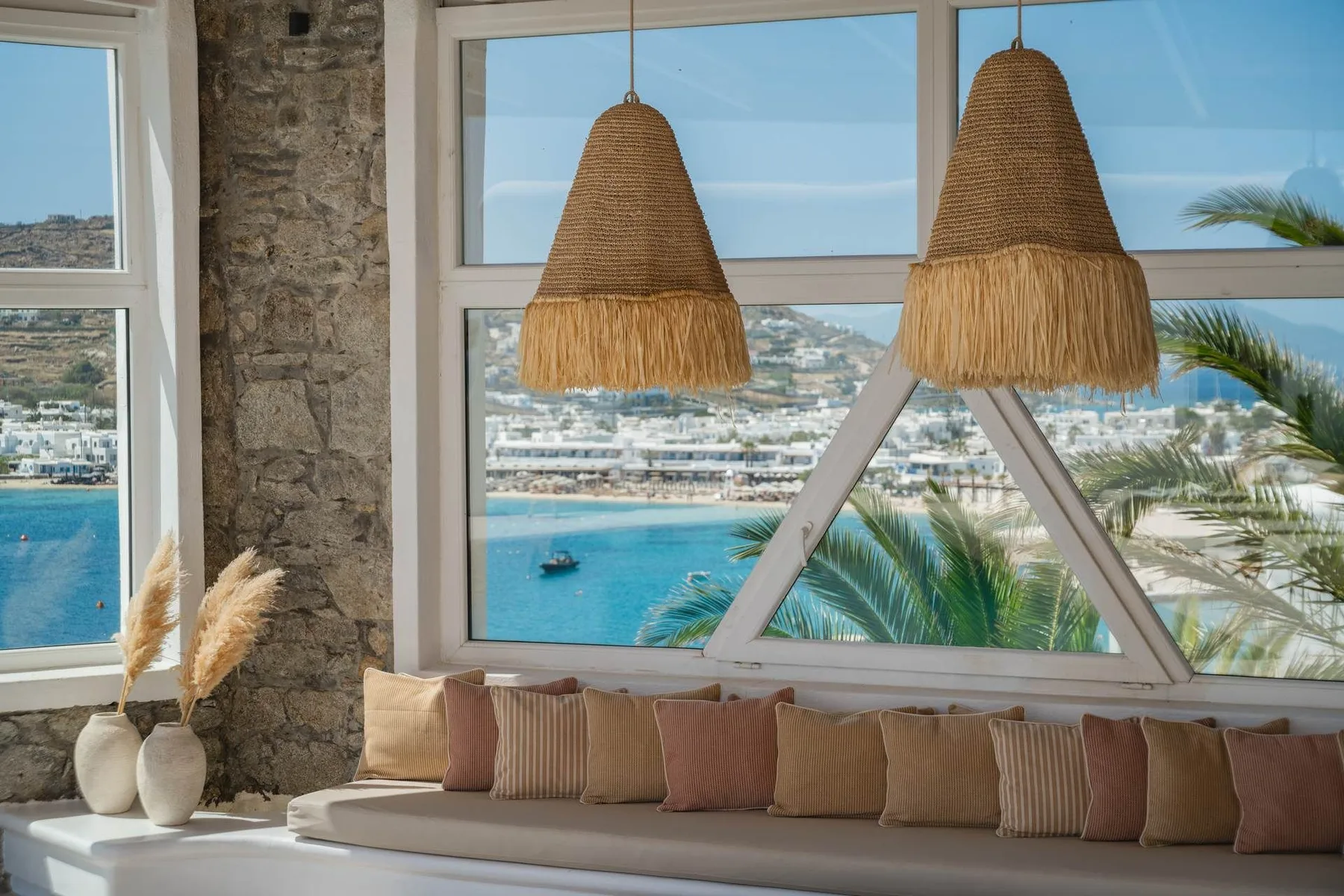 A window-side seating area overlooks the blue water and coastal buildings.