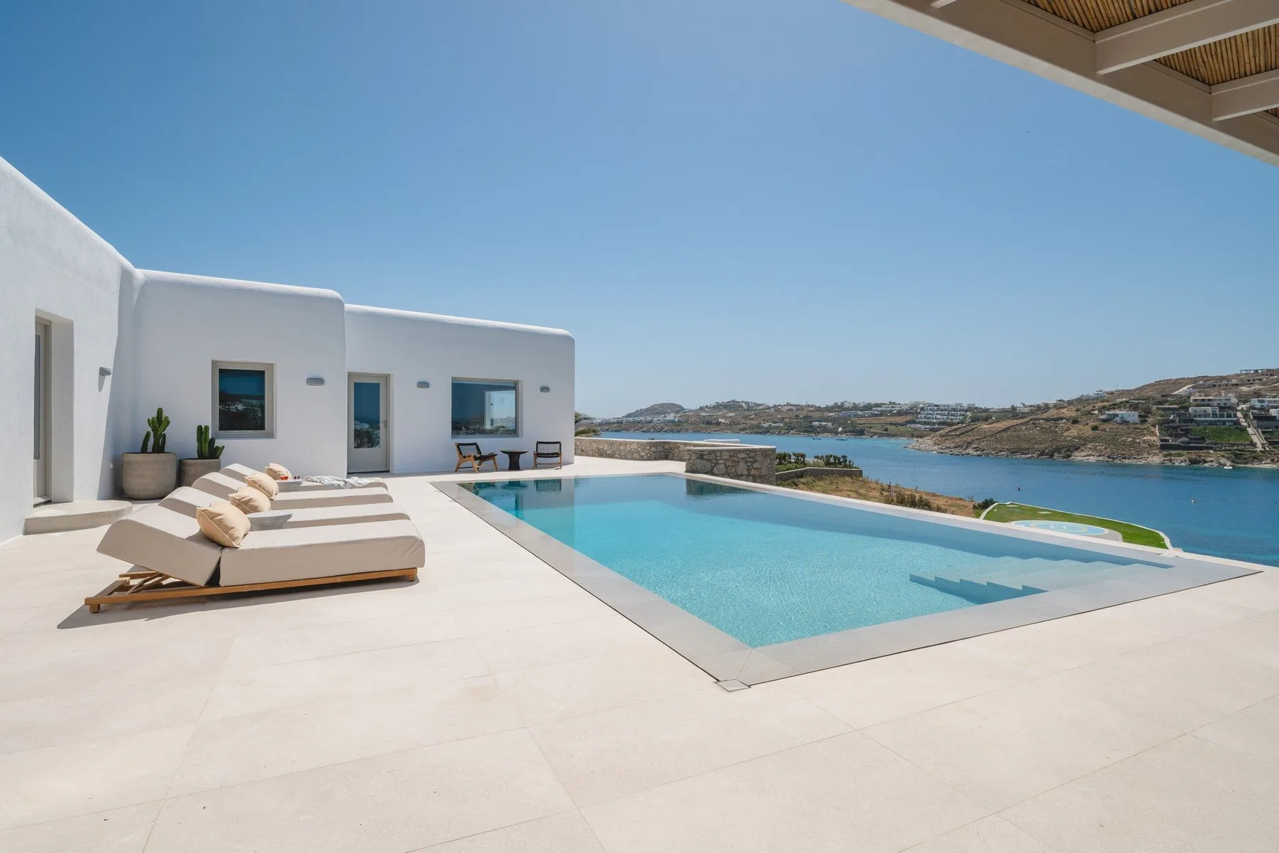 An outdoor pool and lounge area overlook the water and surrounding hills.