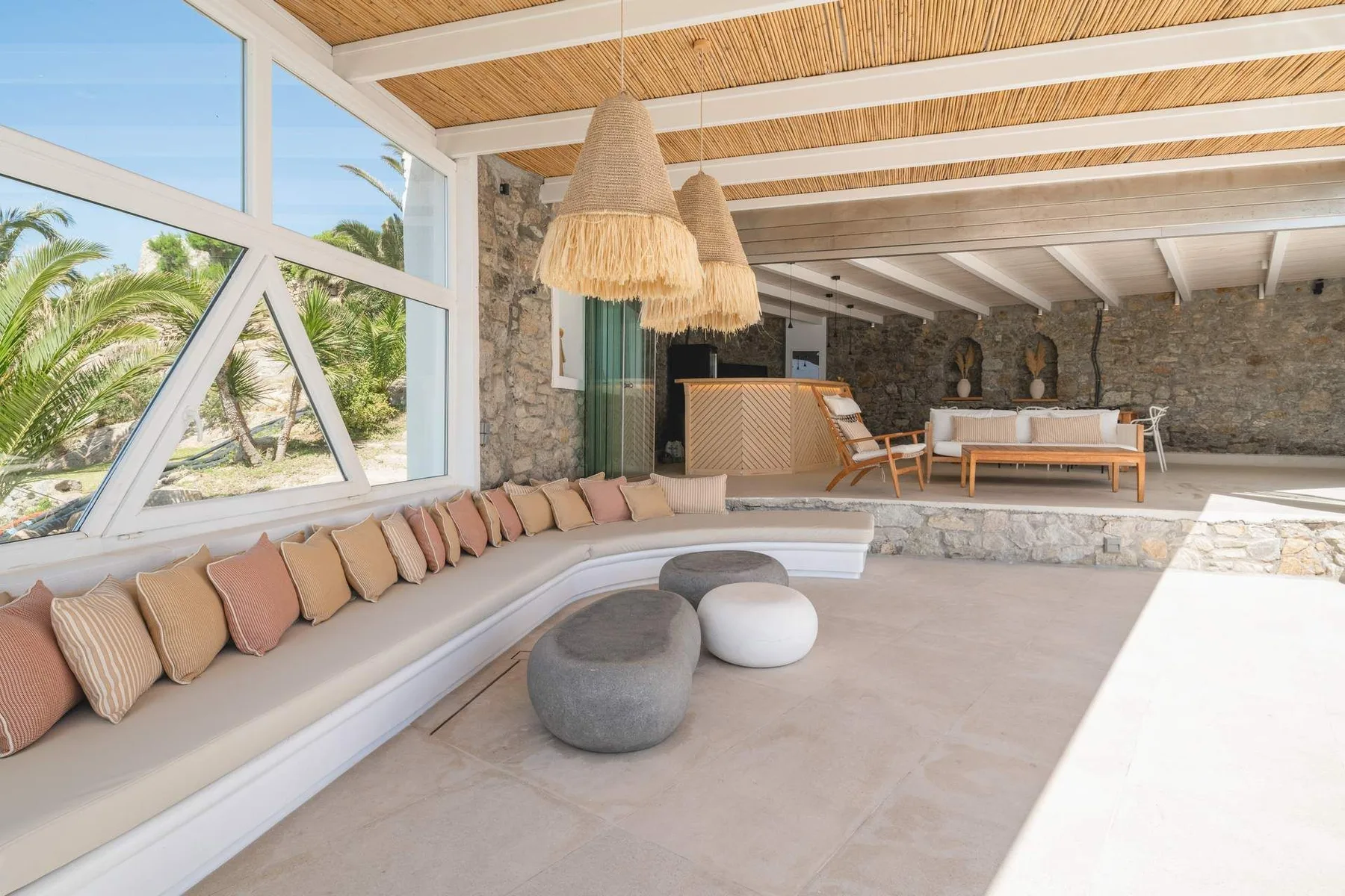 A spacious covered lounge with curved seating and views of palm trees through large windows.