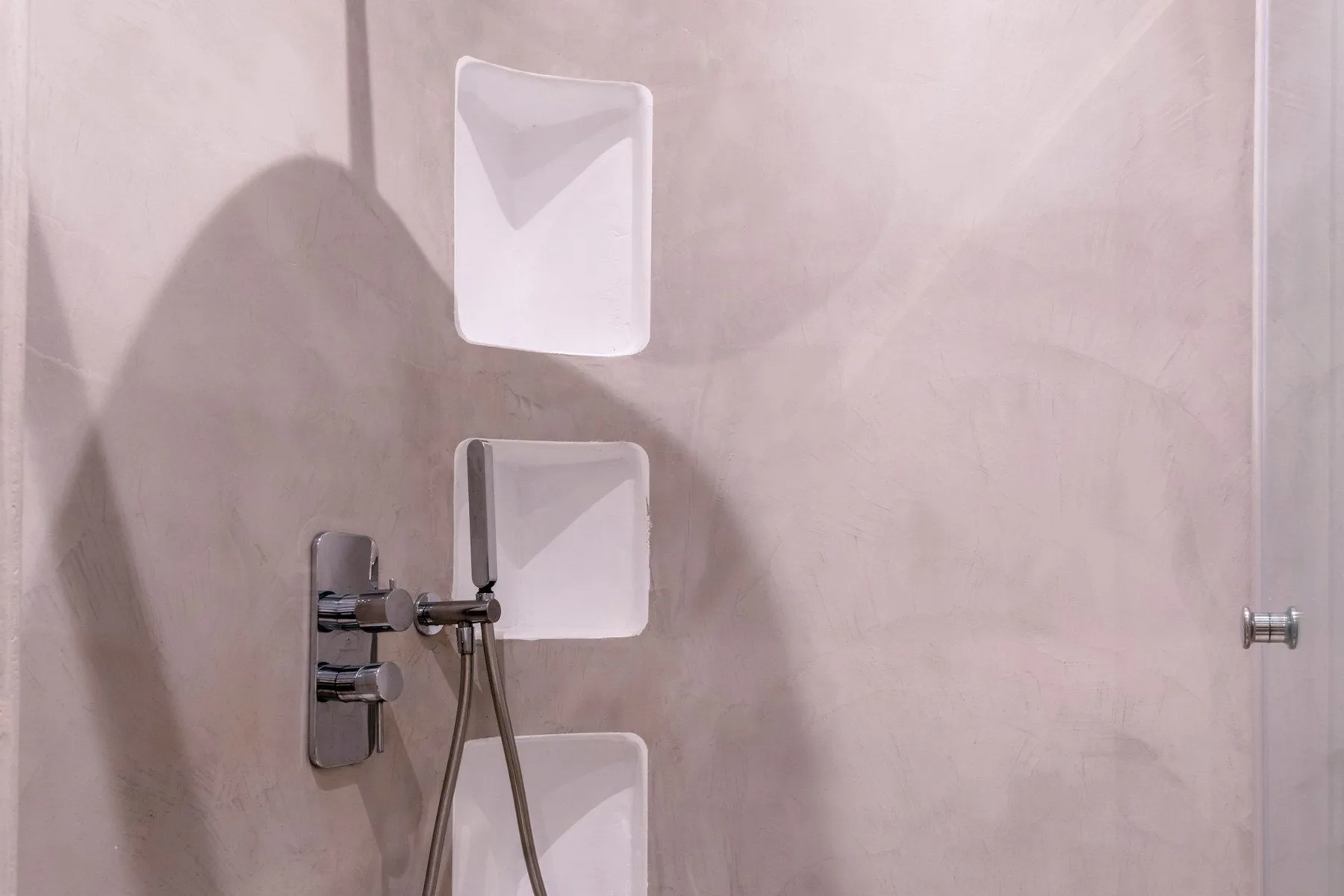 A tiled shower area with recessed wall niches and a handheld shower.