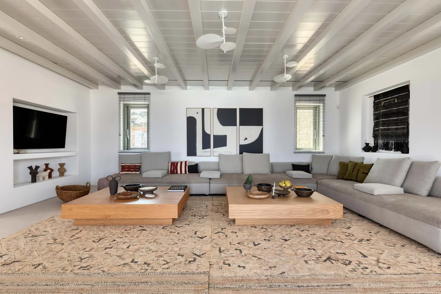 A spacious living room with sectional seating, two low tables, and wall art.