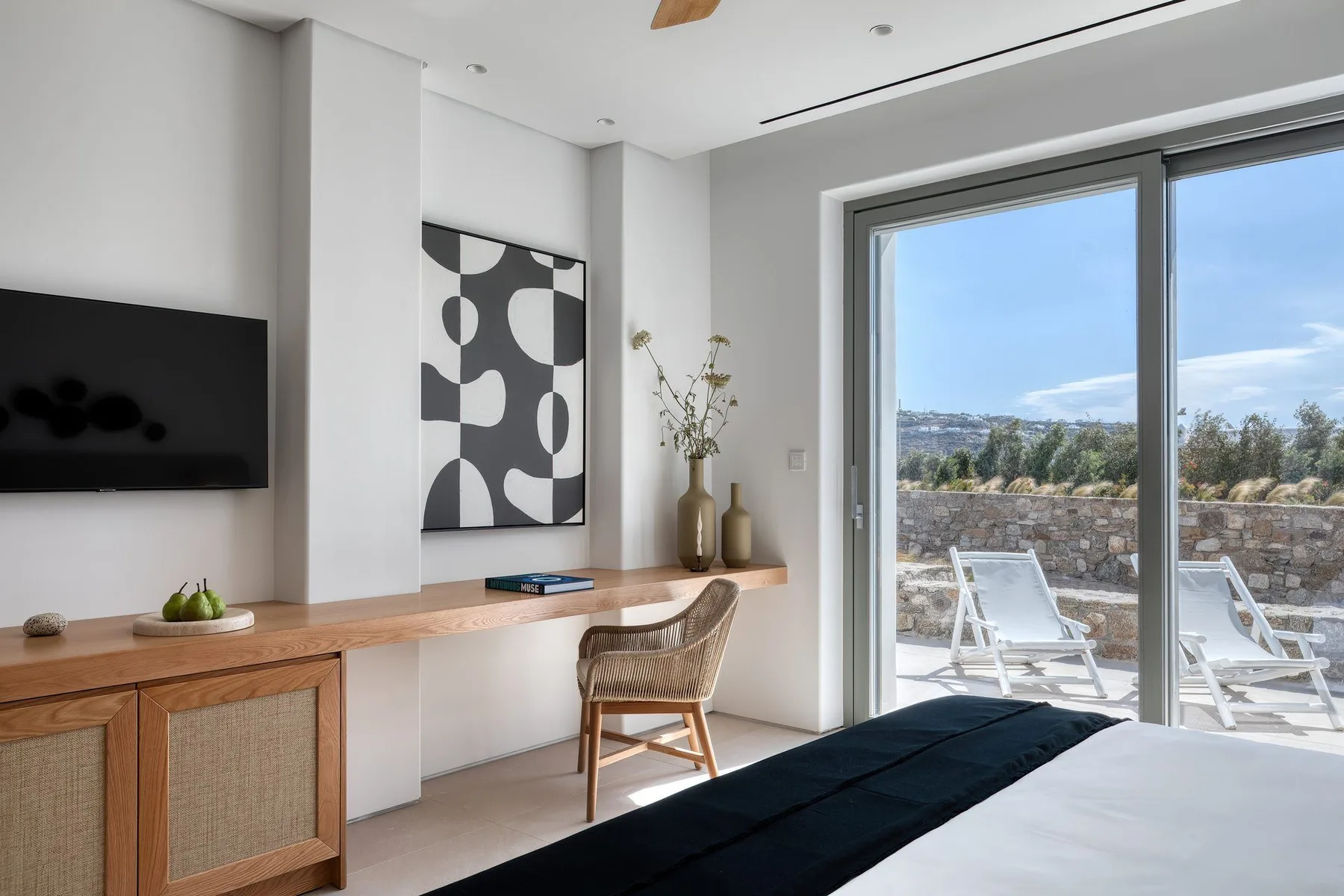A modern living room with a television, artwork, and sliding glass doors opening onto a patio.