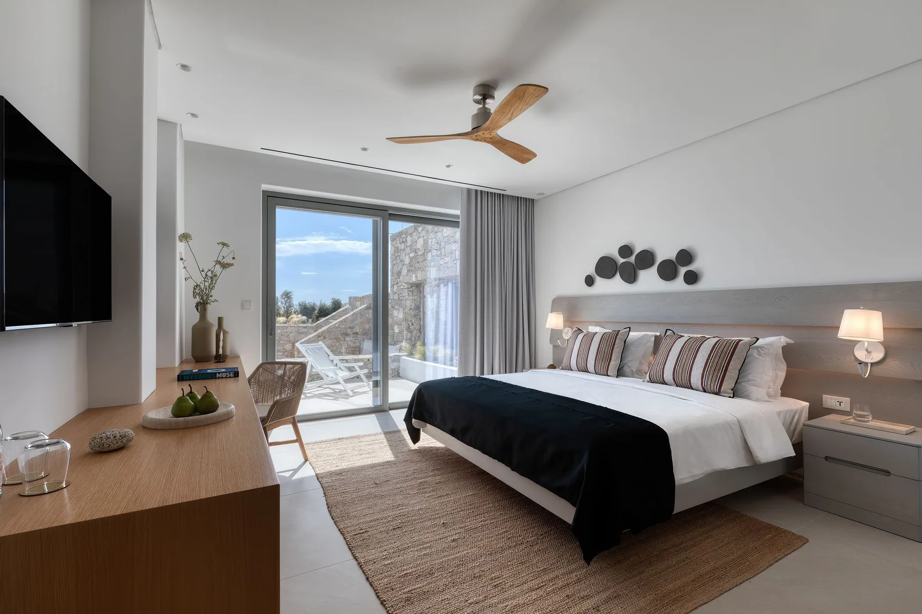 A modern bedroom with a large bed beside sliding glass doors.