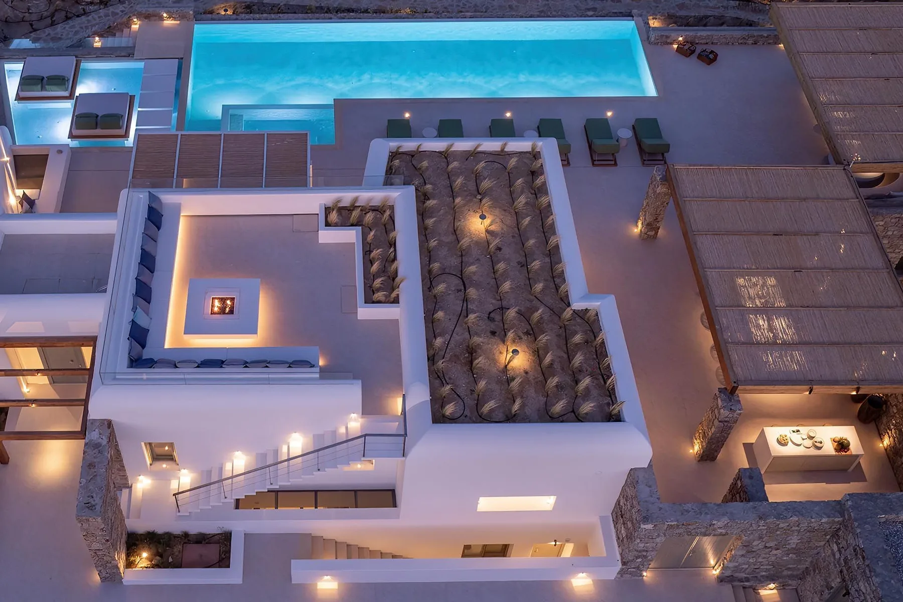 An illuminated rooftop pool and lounge area at dusk.