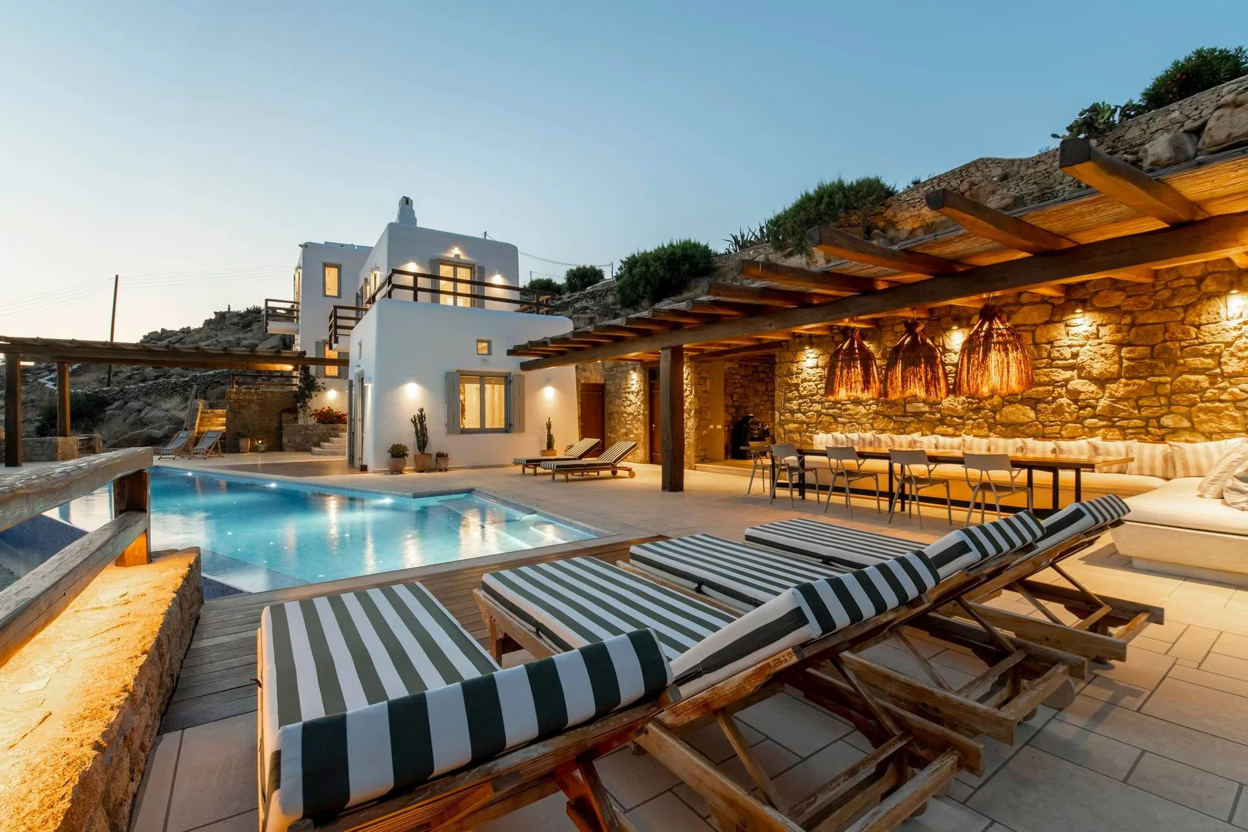 An outdoor pool area with striped loungers and a covered dining space.
