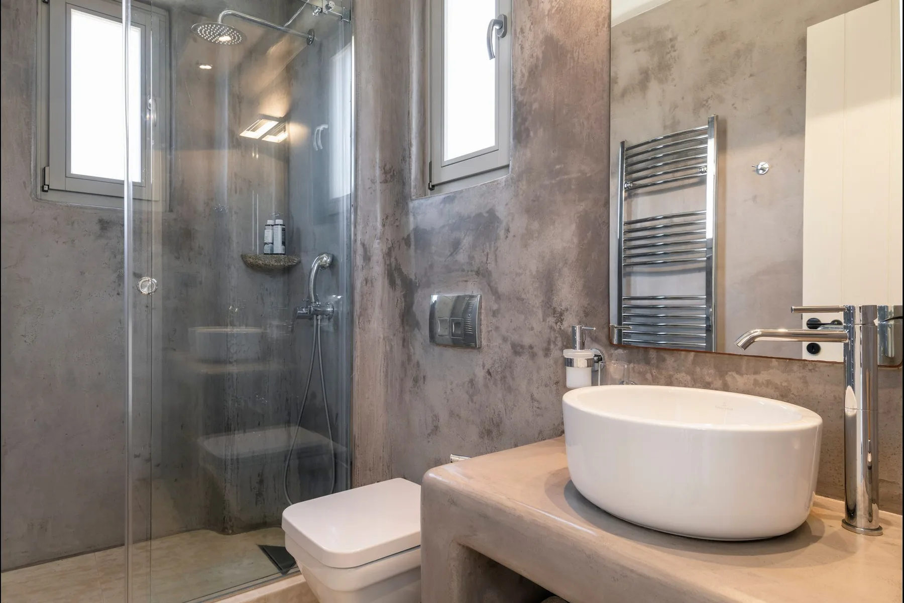 A modern bathroom with a glass shower and a white vessel sink.