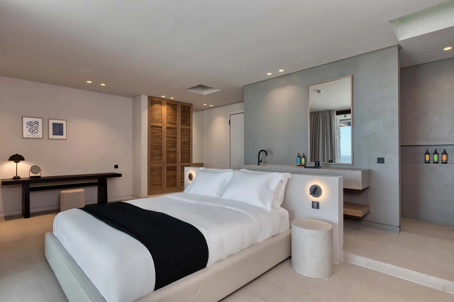 A modern bedroom with a neatly made bed and a desk along the wall.