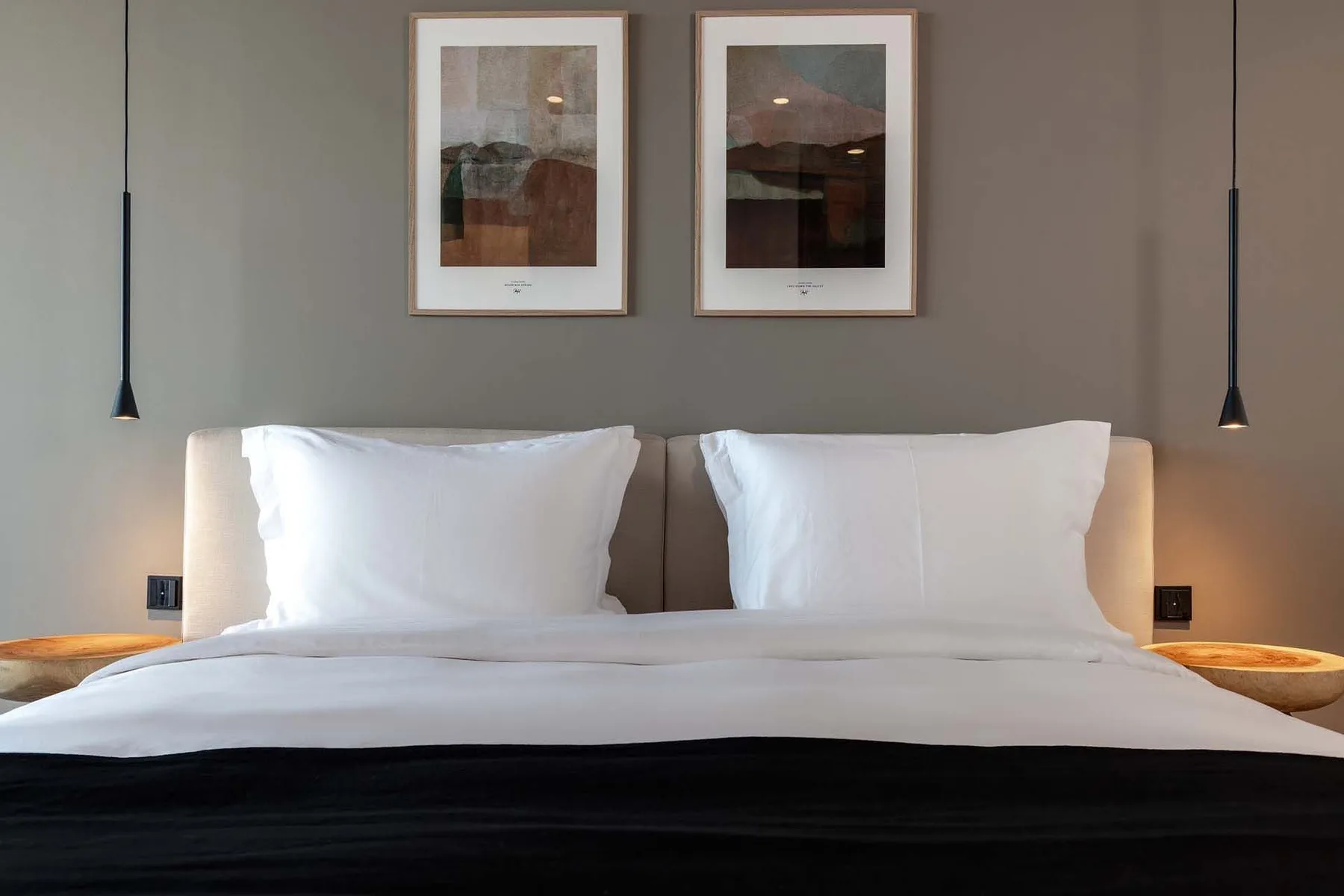 A bedroom with a neatly made bed and framed artwork above the headboard.